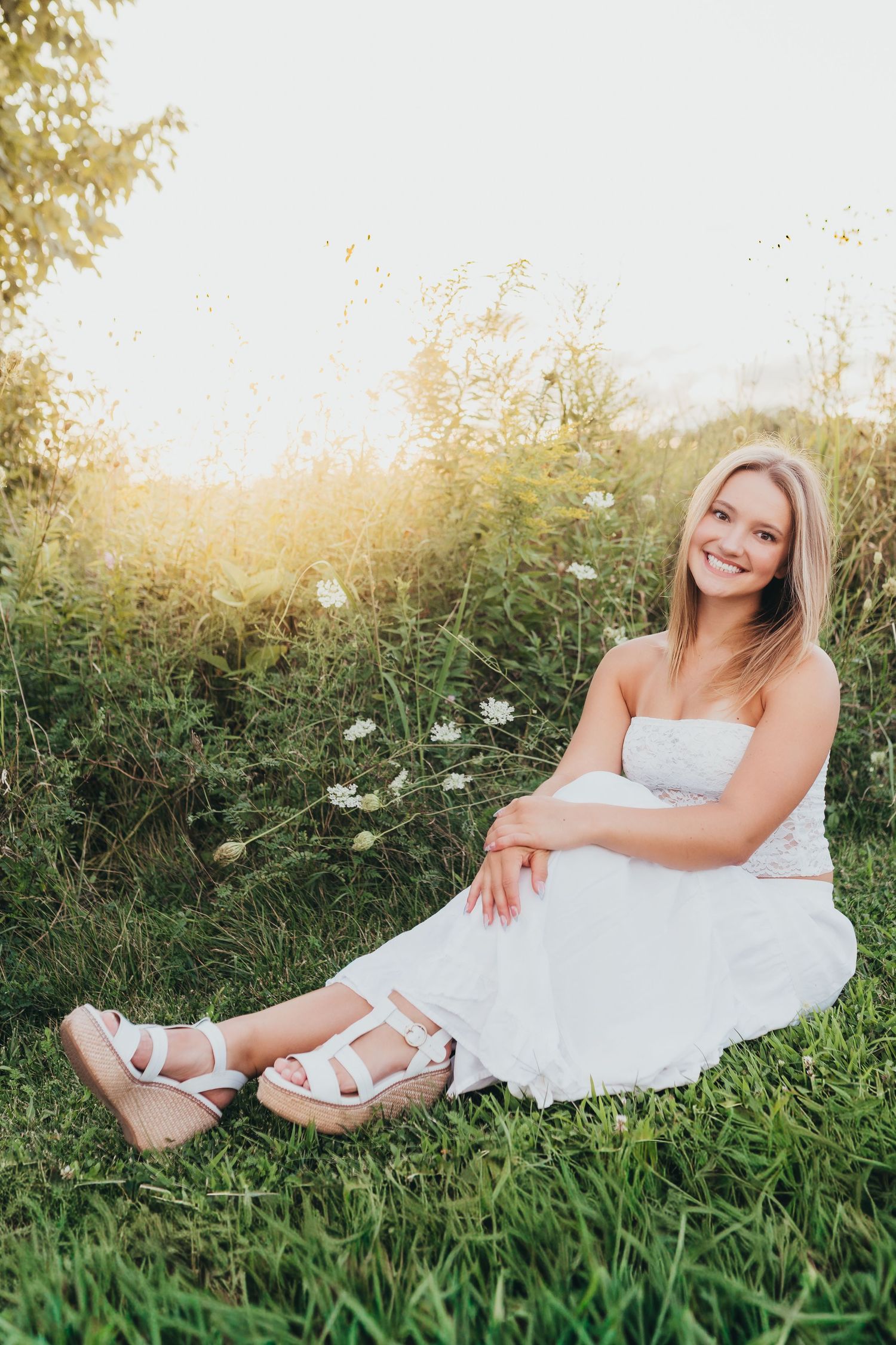 Ethereal summer portrait session in a white dress among wildflowers at golden hour.