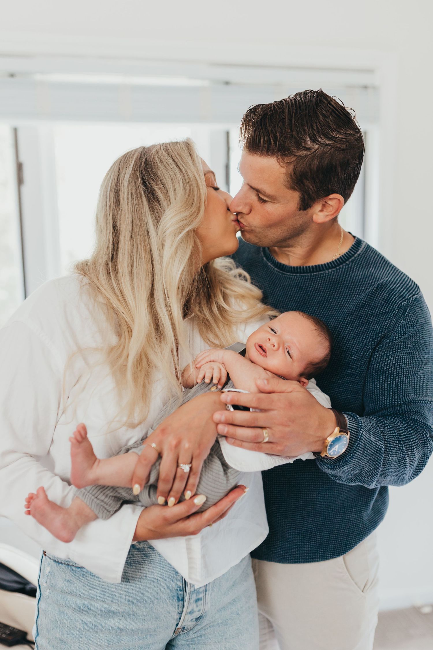 Family sharing intimate moment together in bright white room.
