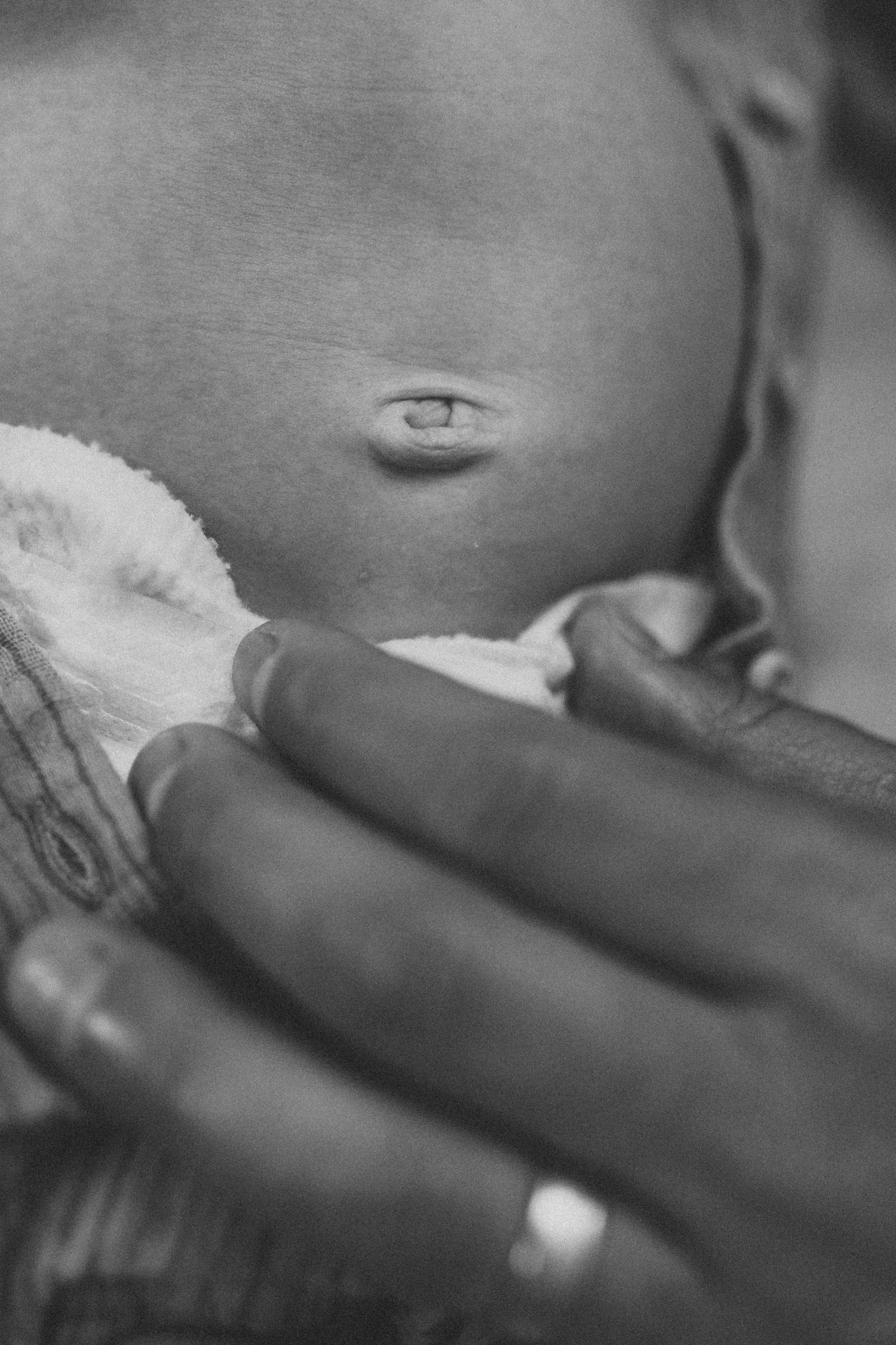 Black and white artistic close-up of baby being held.