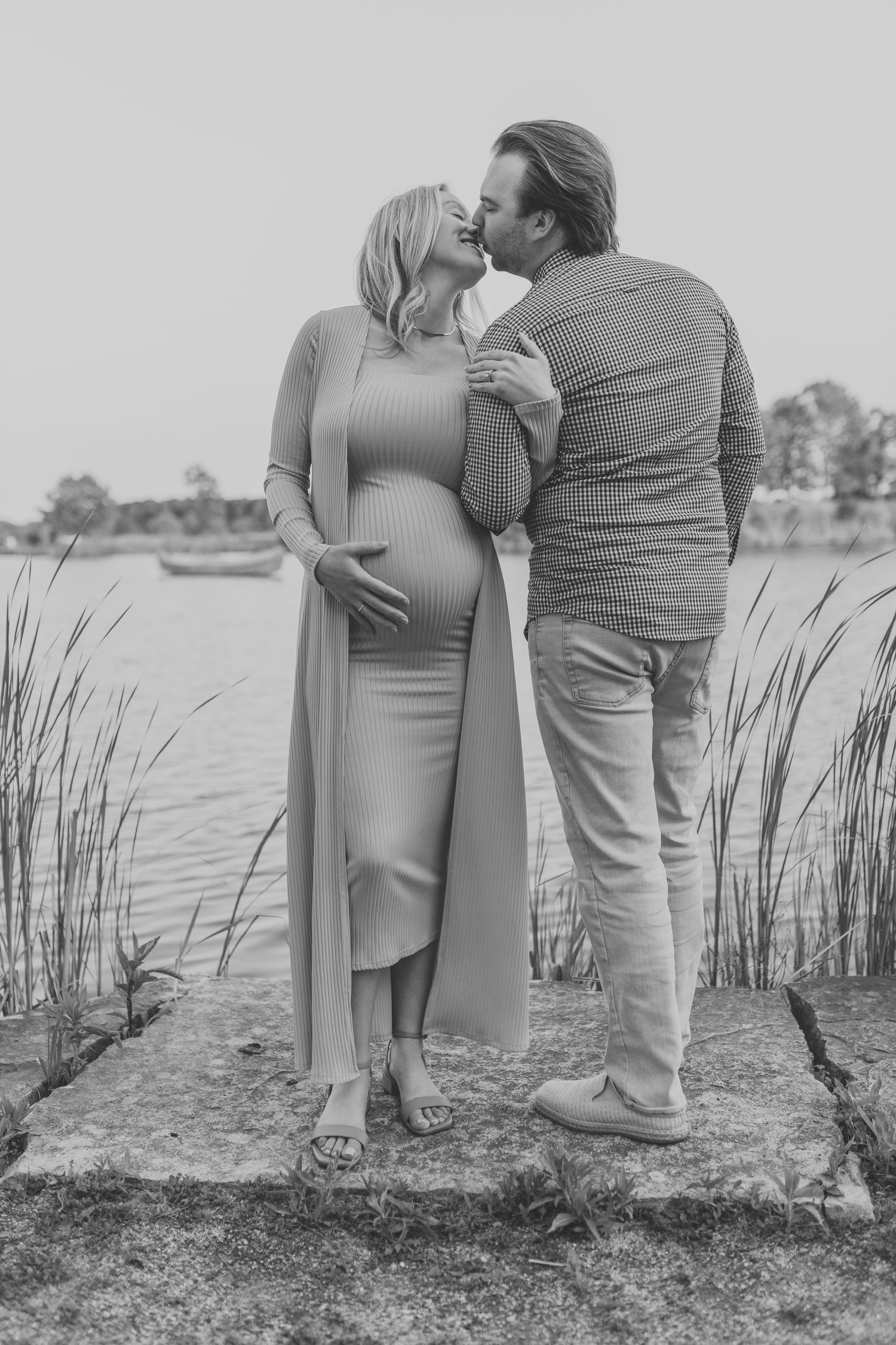 Expecting couple sharing an intimate moment by the water's edge.