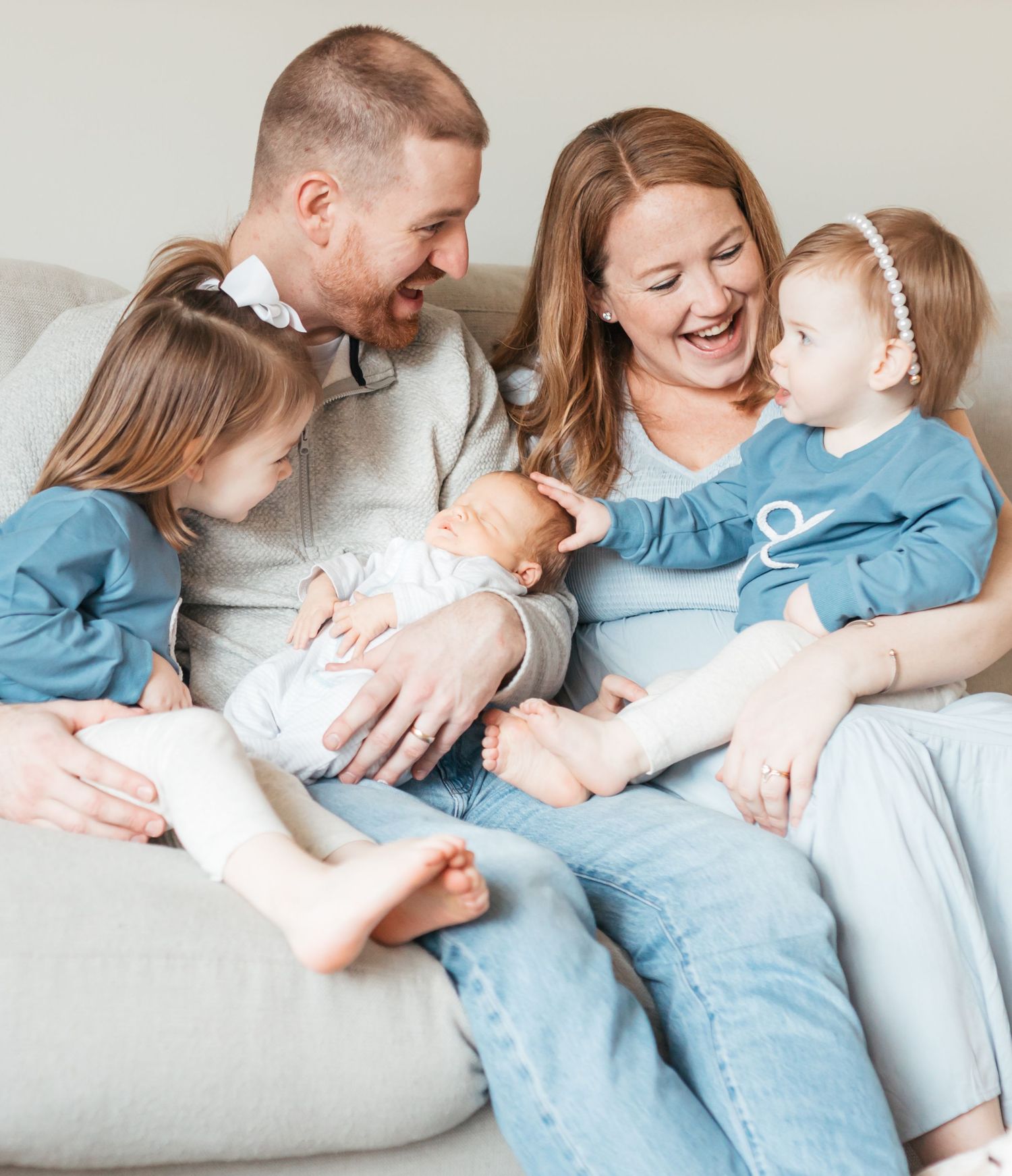 A loving family moment on a couch as they cuddle together in matching blue outfits.