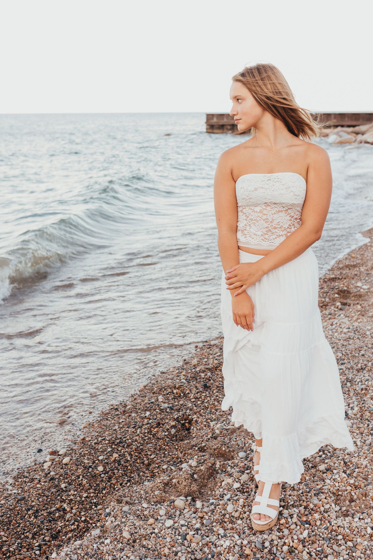 Artistic beach portraits showcase a delicate white lace dress against the water.