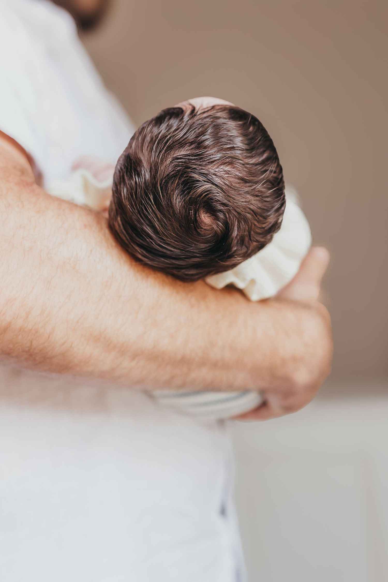 Close-up shots of newborn baby's dark hair against white fabric.