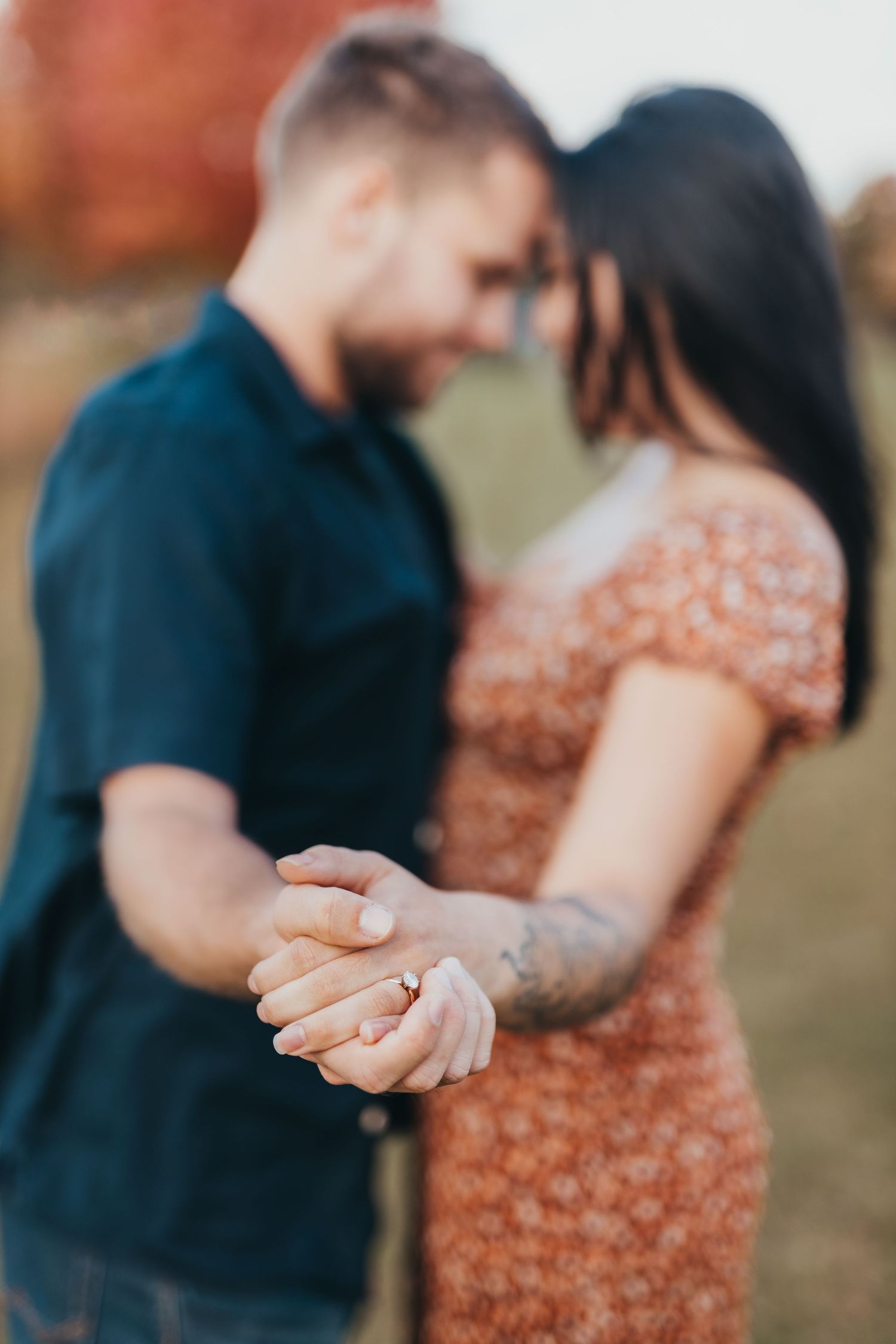 Close-up shot of a couple embracing, with focus on her floral dress and his navy shirt.