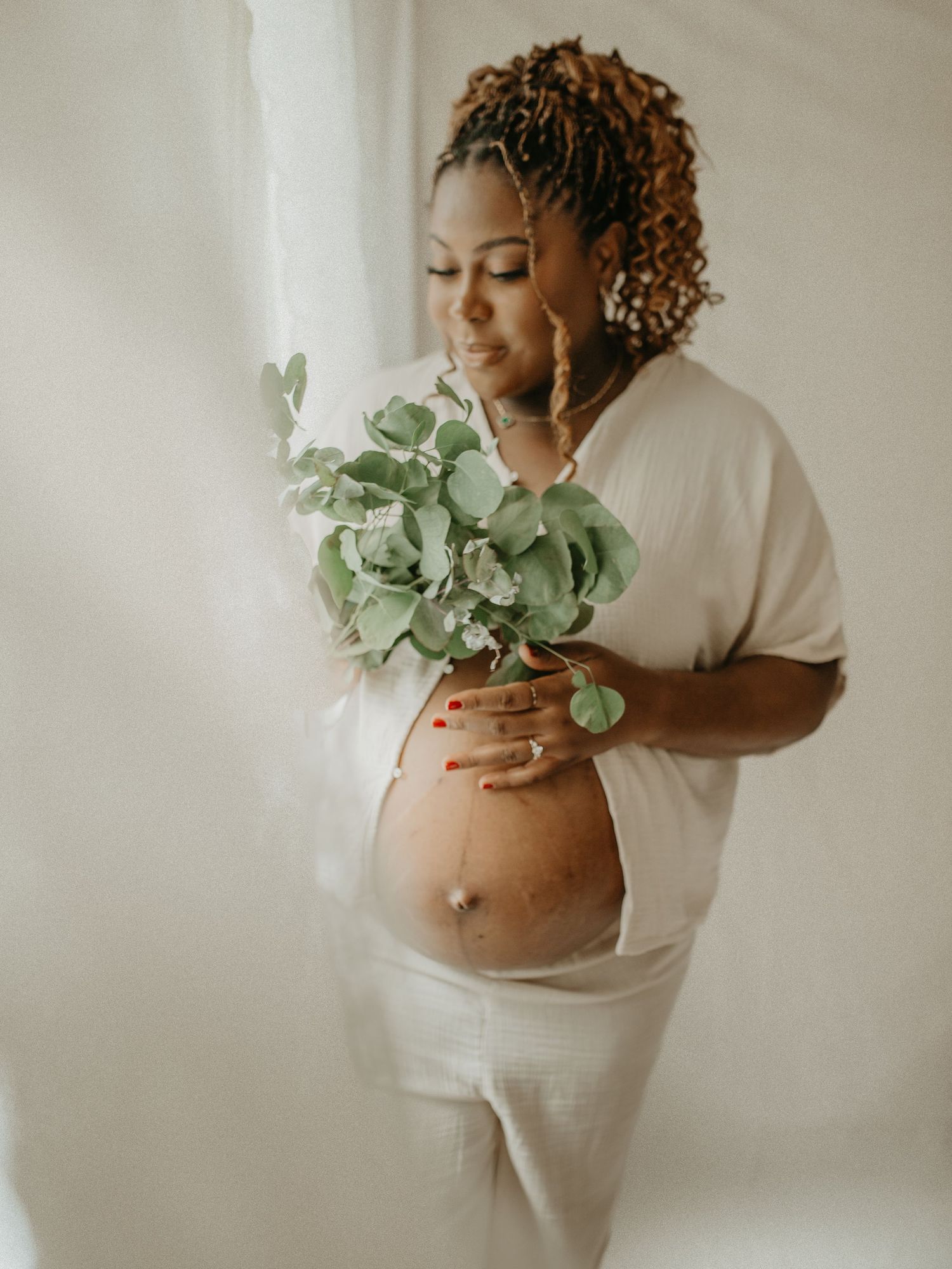 A series of maternity photos showing a pregnant woman in white dress holding eucalyptus leaves against a light background.