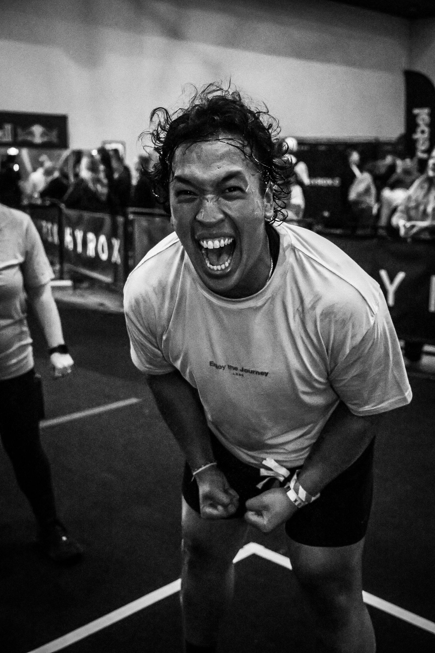 Black and white photo of a man laughing and celebrating at a fitness competition event.