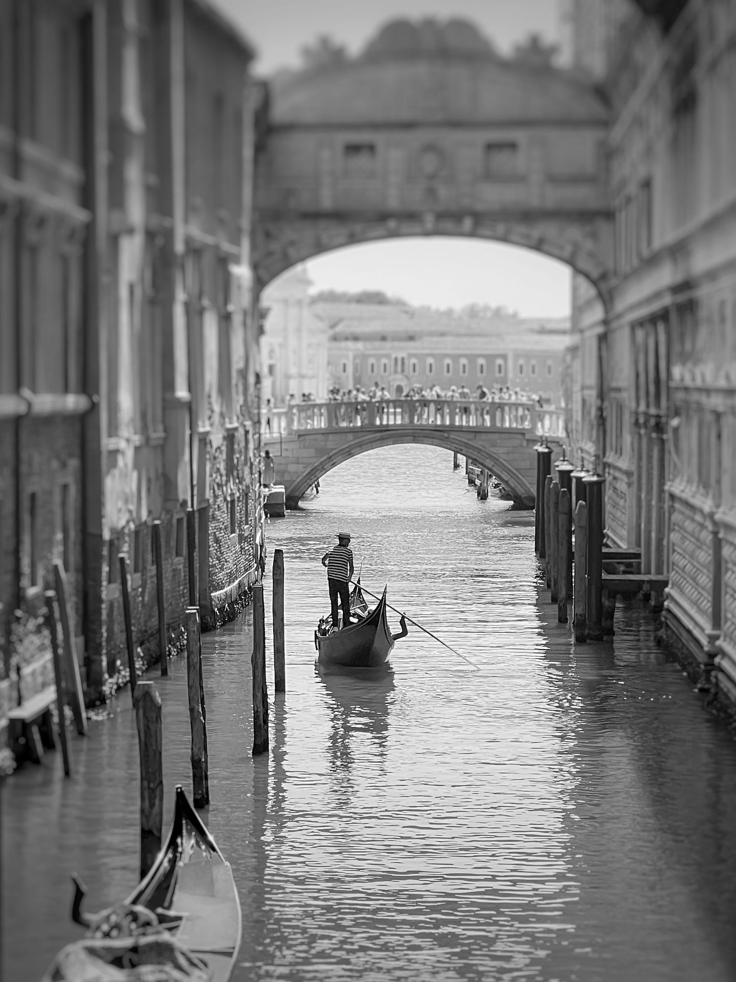 Black-and-white view of a gondola passing beneath the Bridge of Sighs in Venice, Italy.