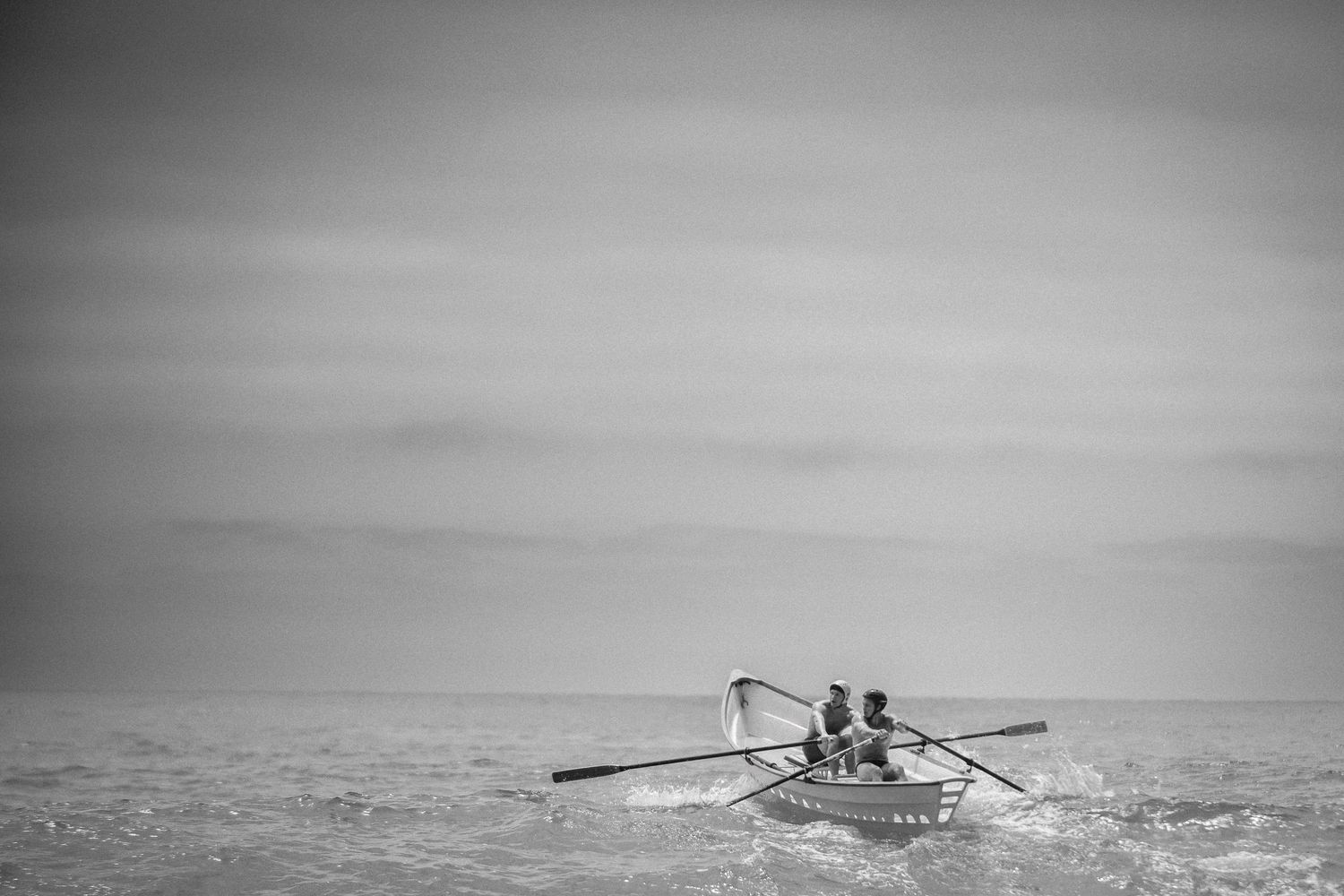 Two dory rowers crossing the ocean off San Clemente, California, in a black-and-white photograph.