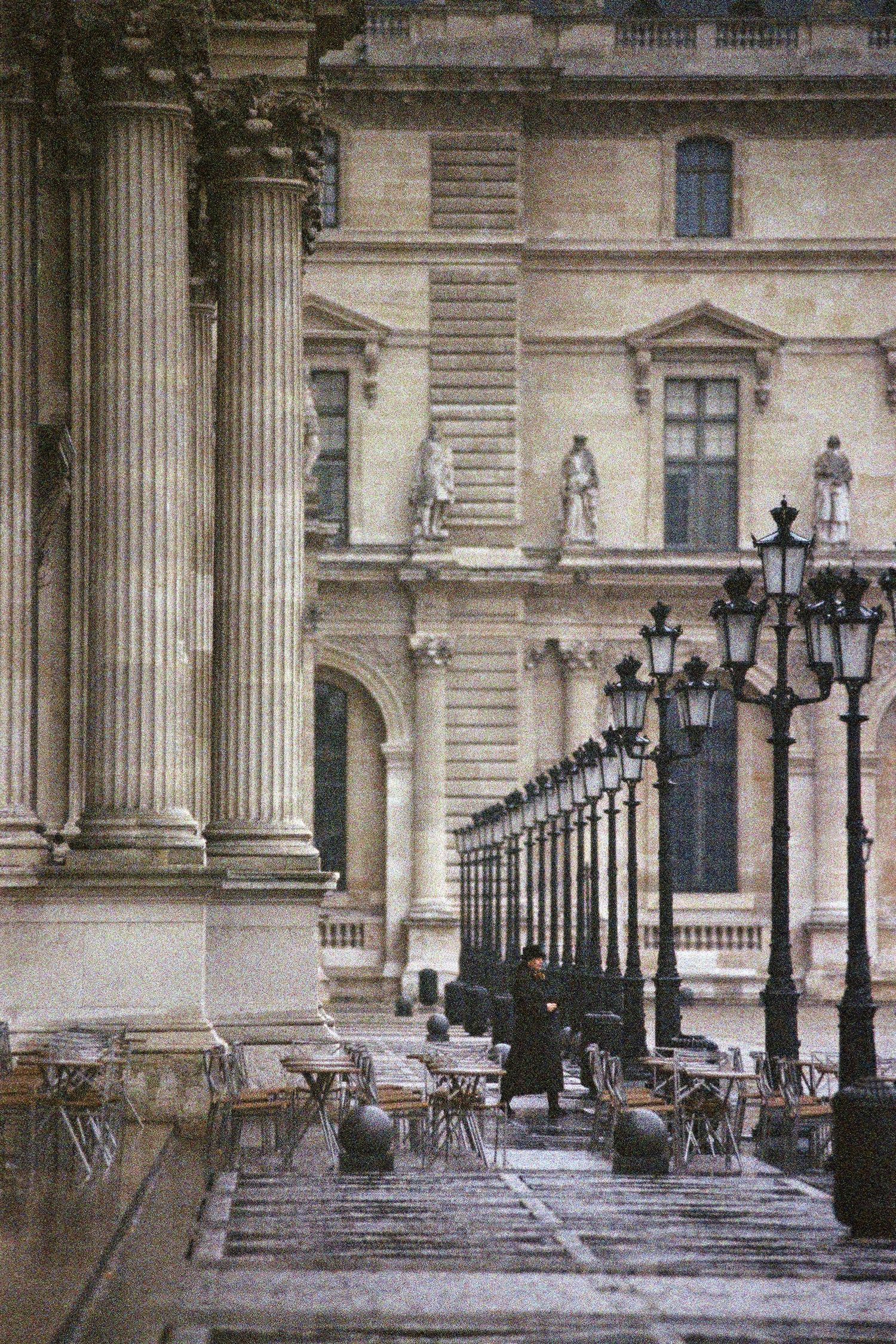 Rain-wet courtyard and classical stone architecture at the Louvre Museum in Paris, France.