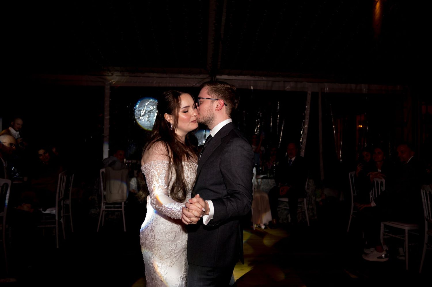 Newlywed couple sharing a romantic first kiss on the dance floor at their wedding reception.