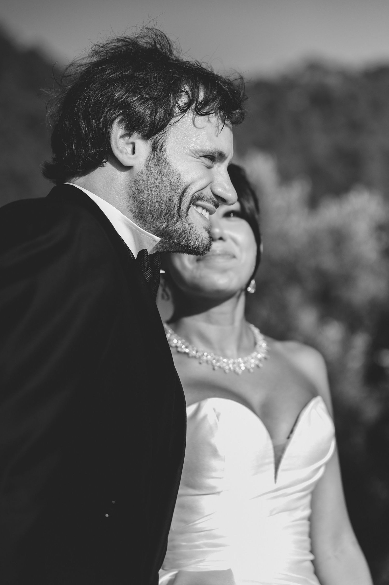 Black and white portrait of smiling groom and bride sharing a tender moment outdoors.