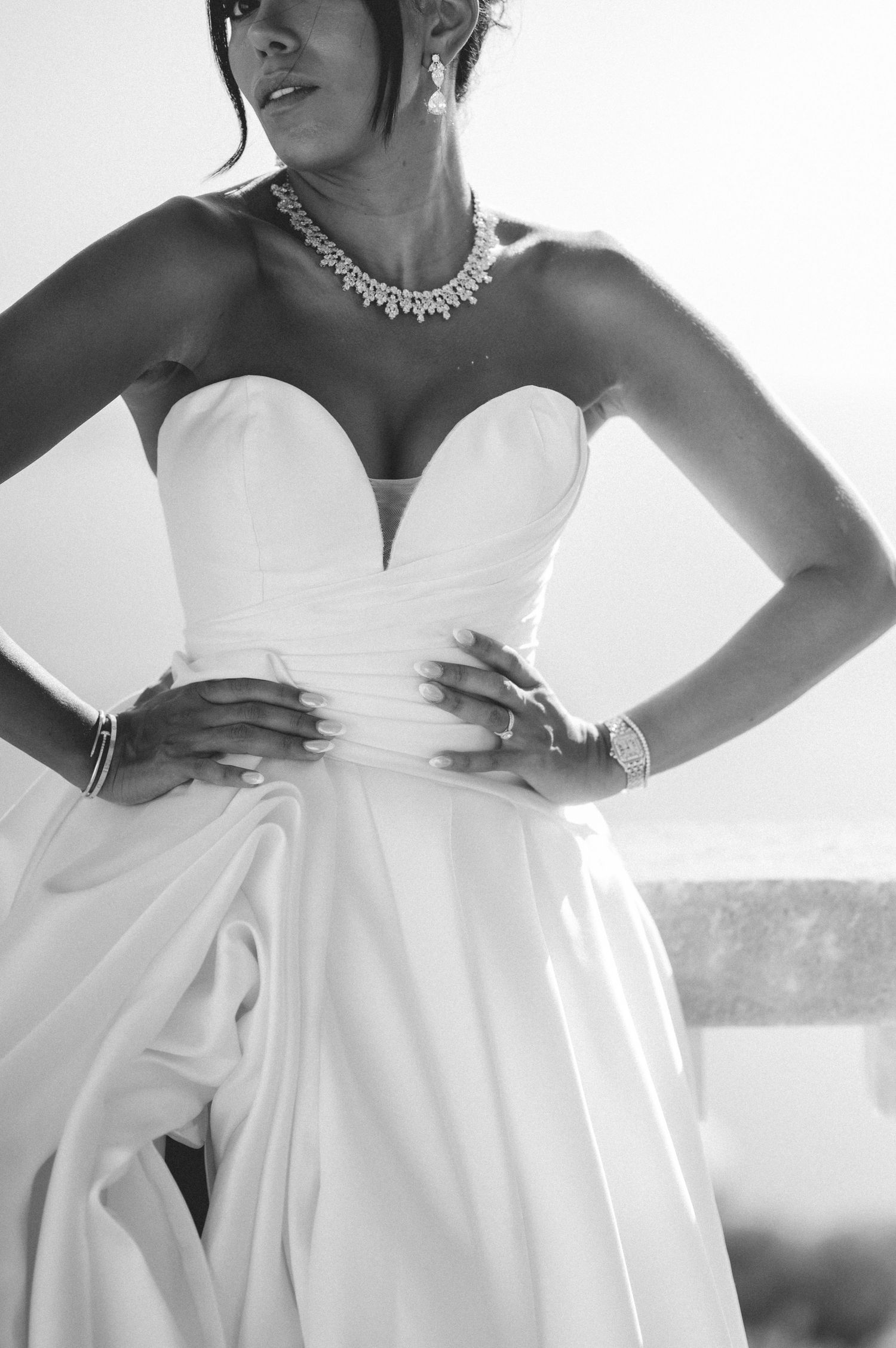 Black and white close-up of bride in strapless white gown with diamond necklace and bracelet.