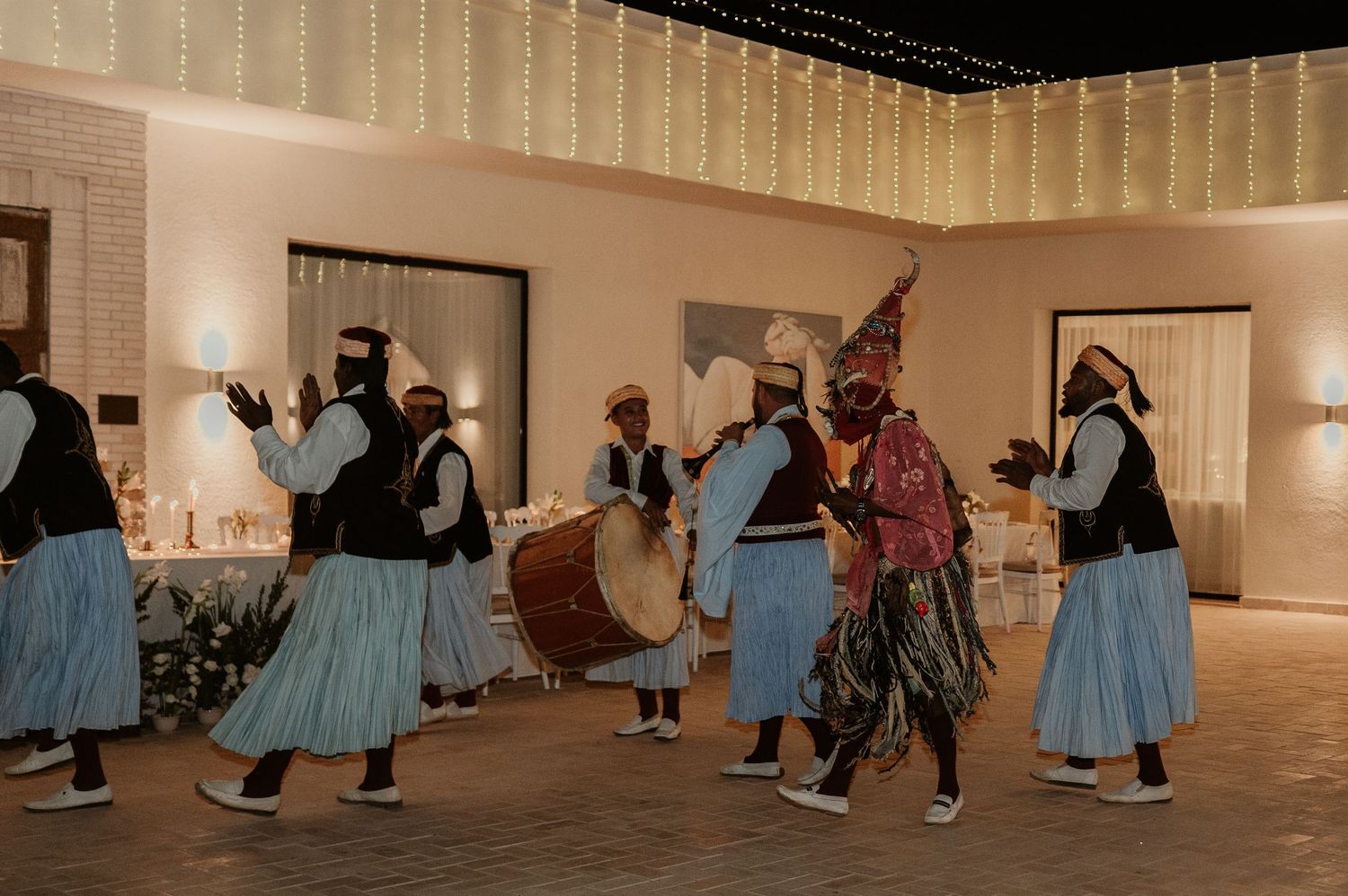 Traditional Gnawa musicians performing in blue and white costumes at a wedding.