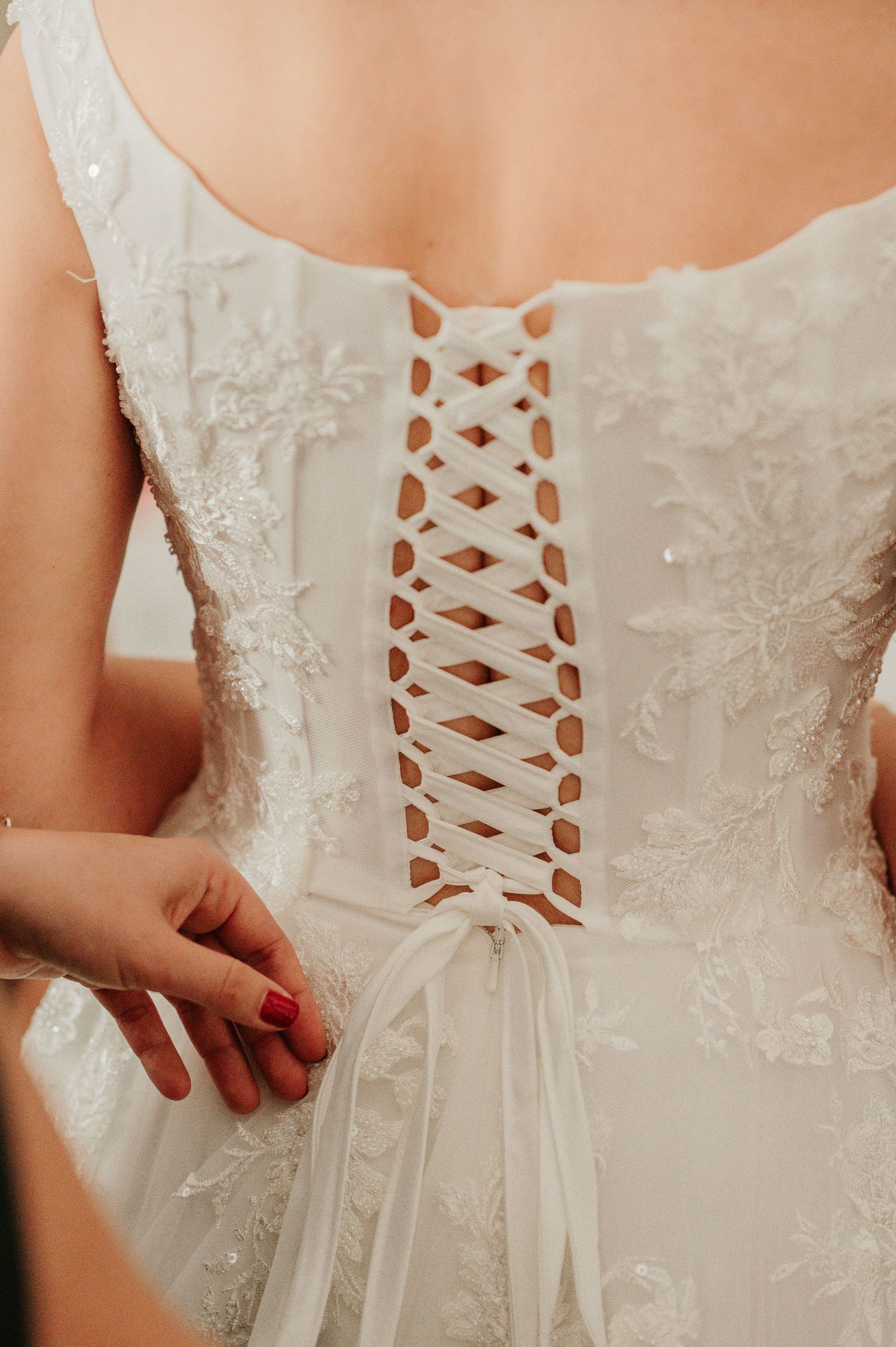 Close-up of intricate corset lace-up back detail on white floral wedding gown.