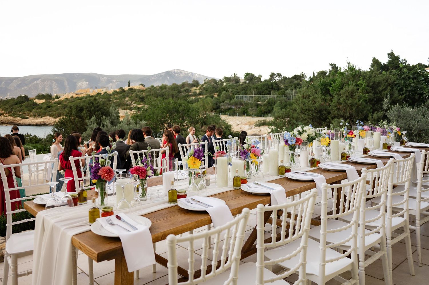 Elegant outdoor wedding reception with long decorated tables, white chairs, and mountain views.