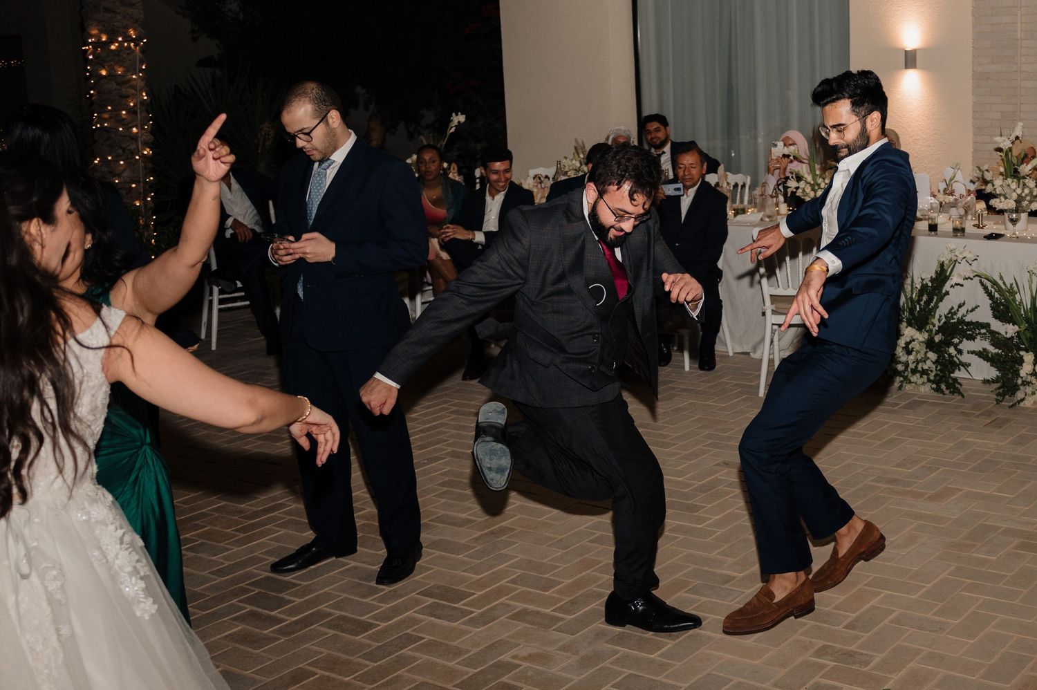 Wedding guests doing lively dance moves on the indoor reception dance floor.
