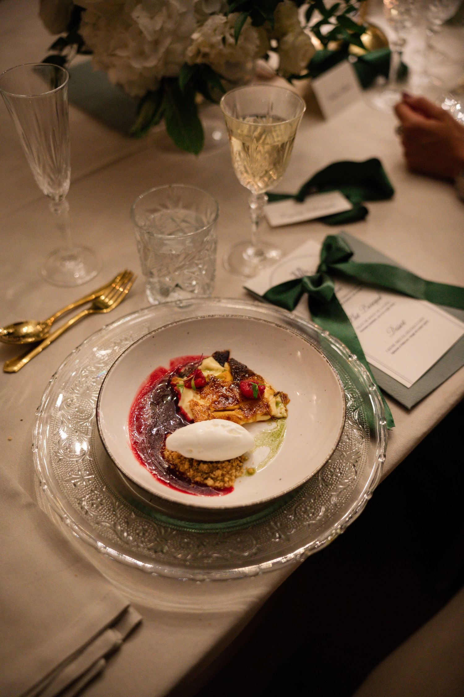 Exquisite wedding dessert with berry compote, cream, and pastry served on silver charger with champagne nearby.