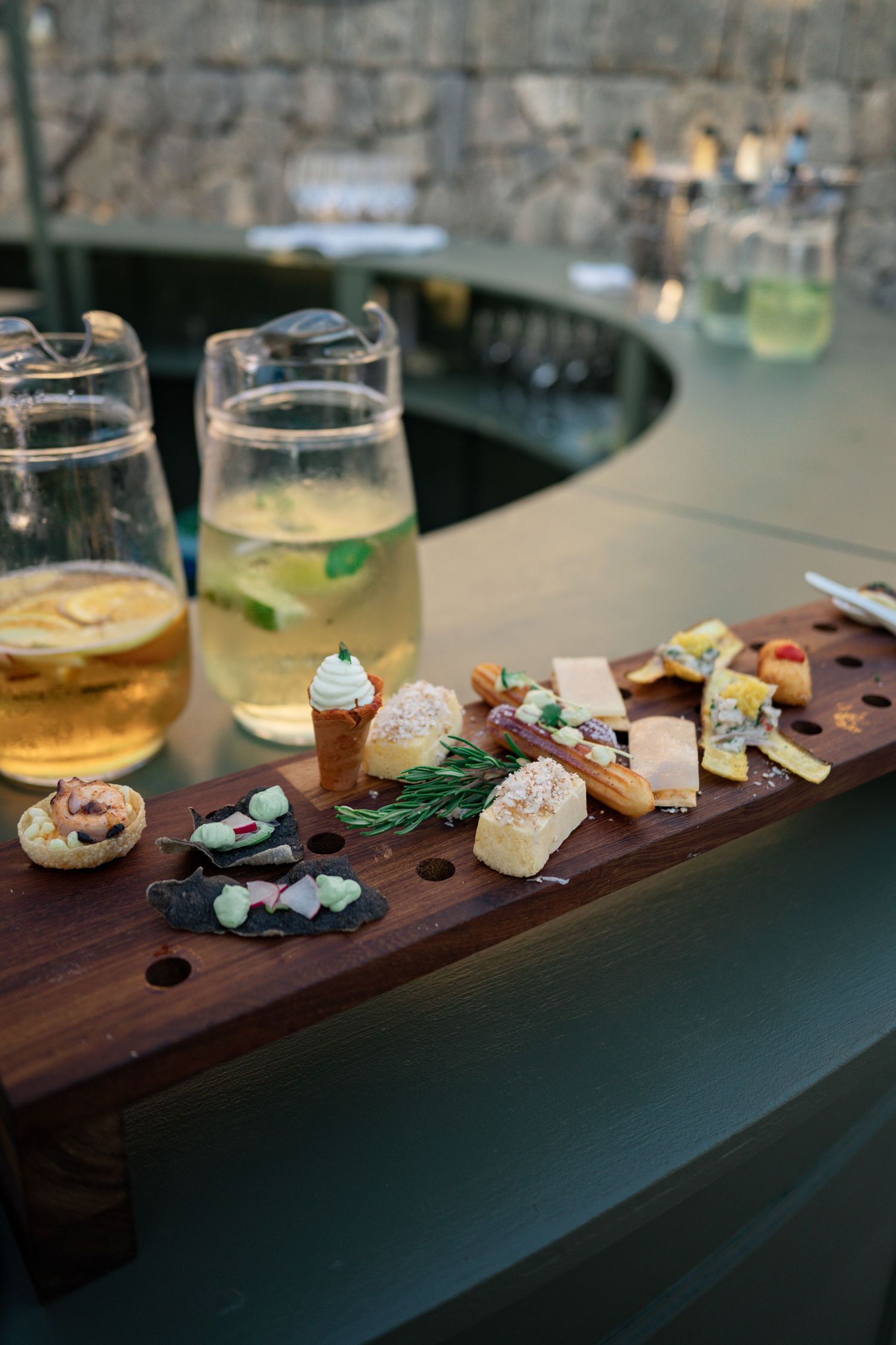 Elegant wedding cocktail hour charcuterie board with cheese, canapés and refreshing drinks on a circular bar.