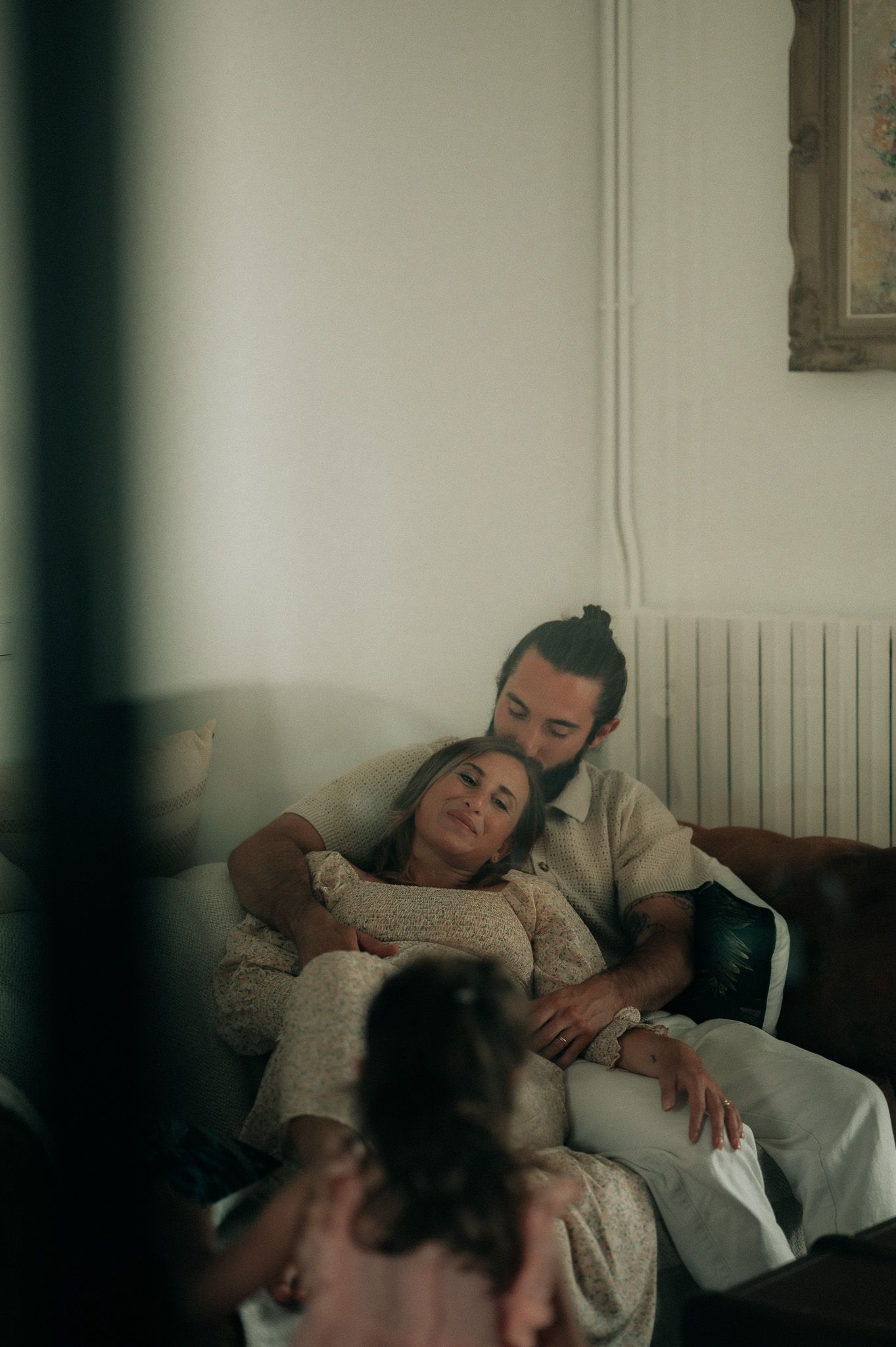 Couple relaxing together on sofa with child in foreground in cozy home interior.