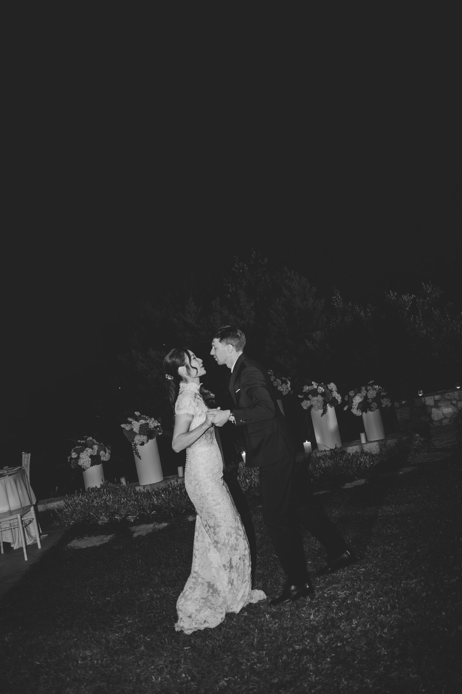 Bride and groom sharing a romantic first dance outdoors at night in black and white.