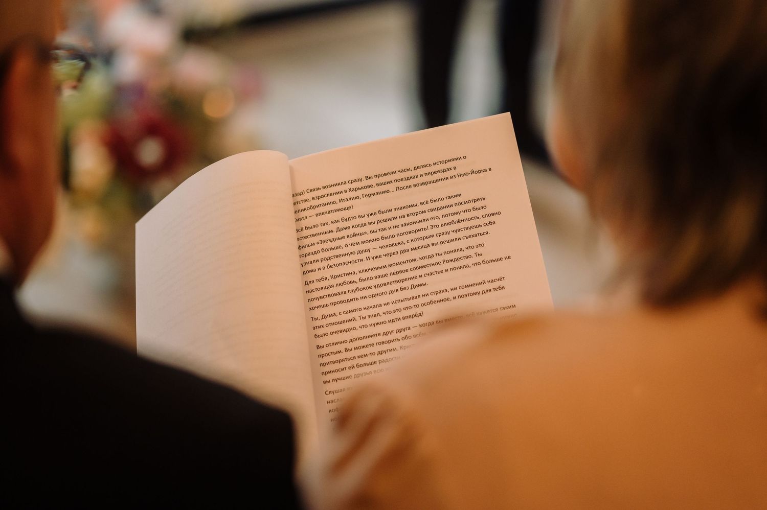 A wedding guest reads from a ceremony program booklet during the wedding service.