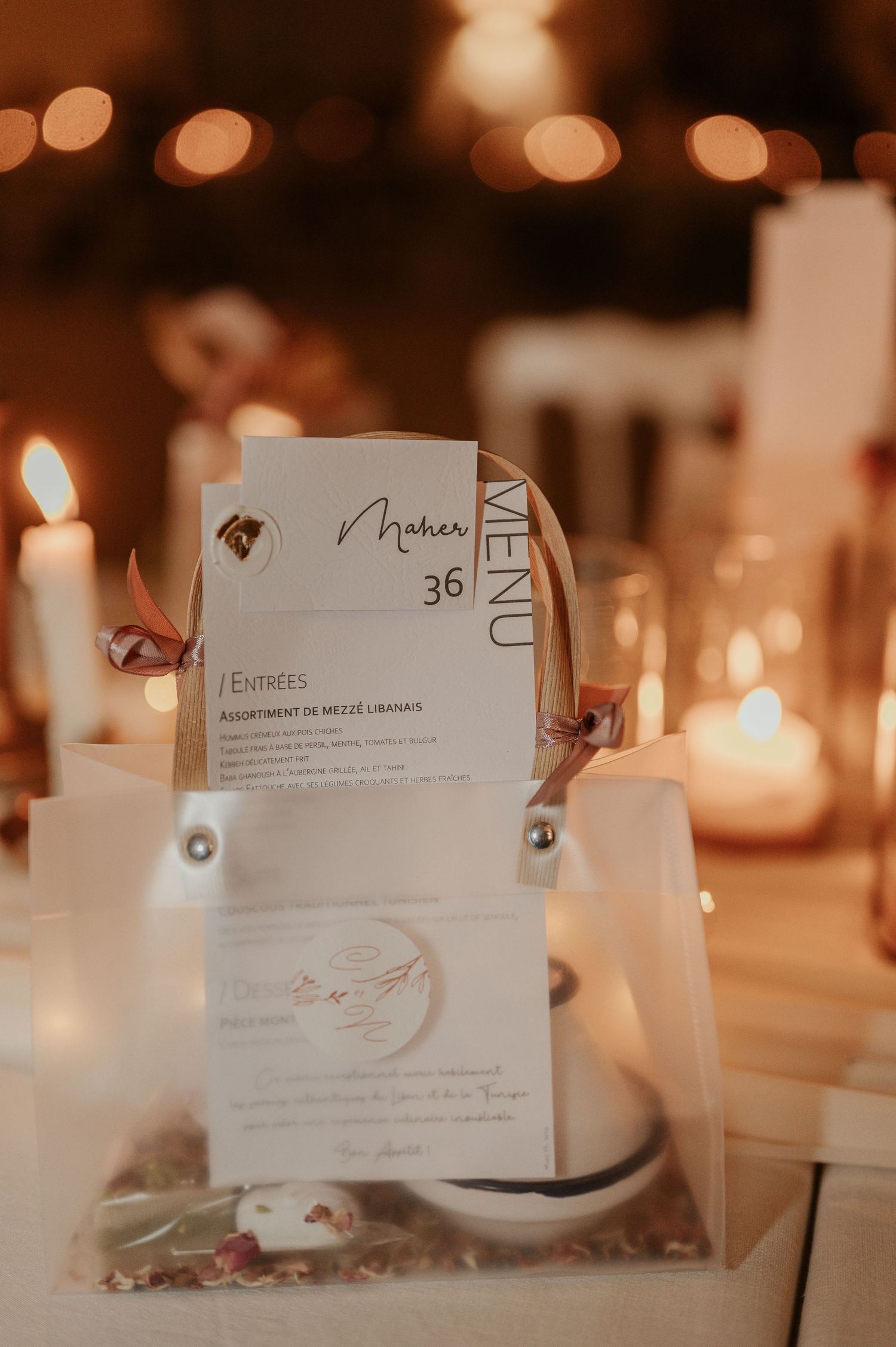 Wedding menu card and stationery displayed with candles and soft warm lighting at reception.