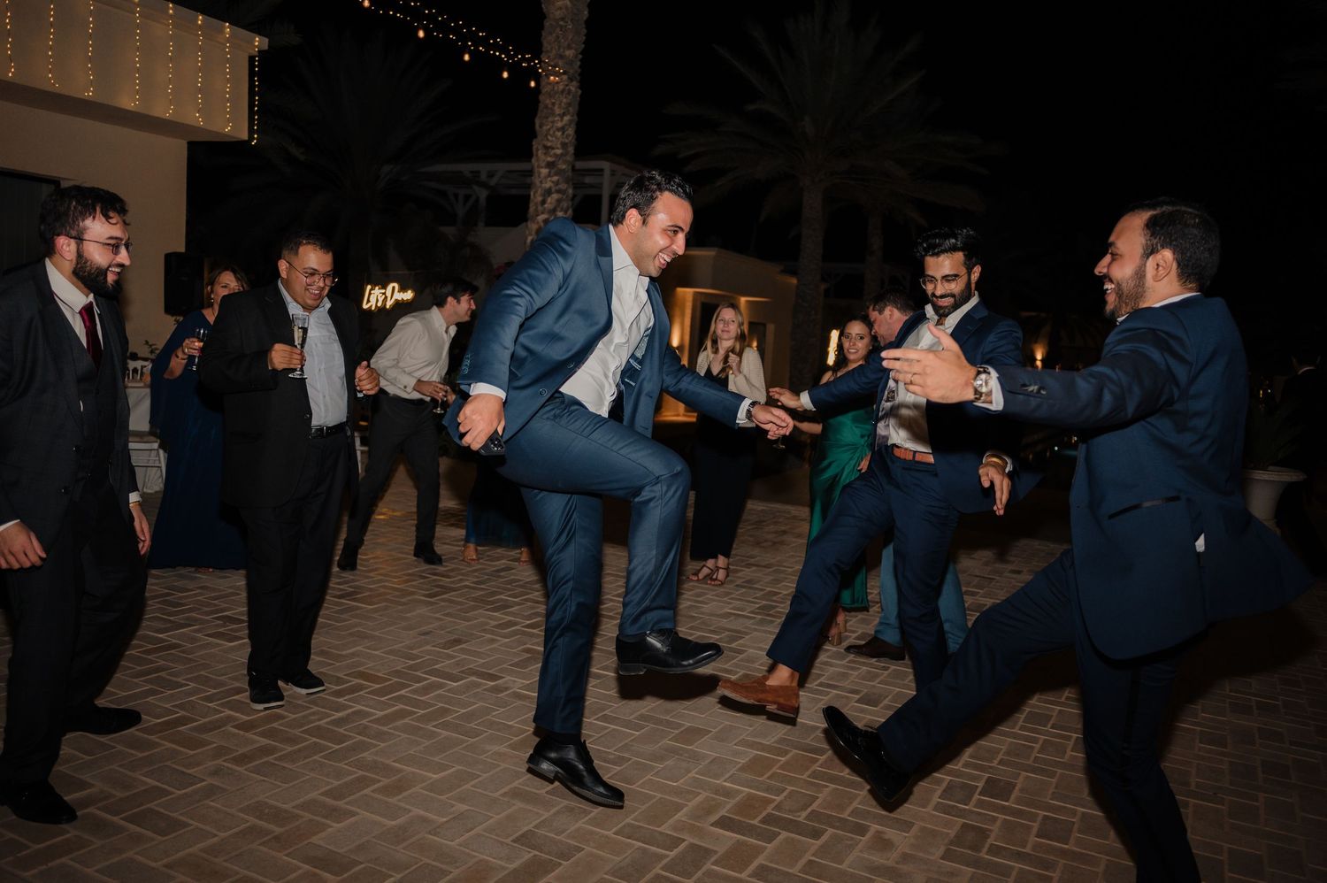 Guests dancing energetically outdoors at a nighttime wedding reception celebration.