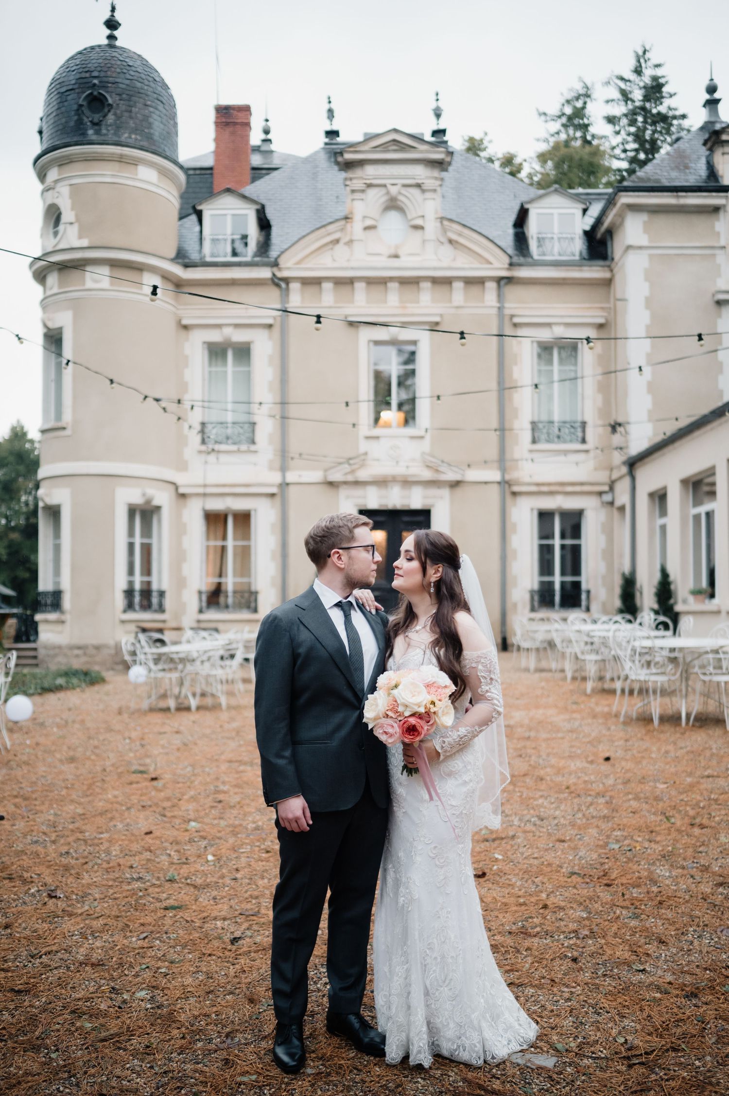 Bride and groom share a romantic moment in front of an elegant French chateau wedding venue.