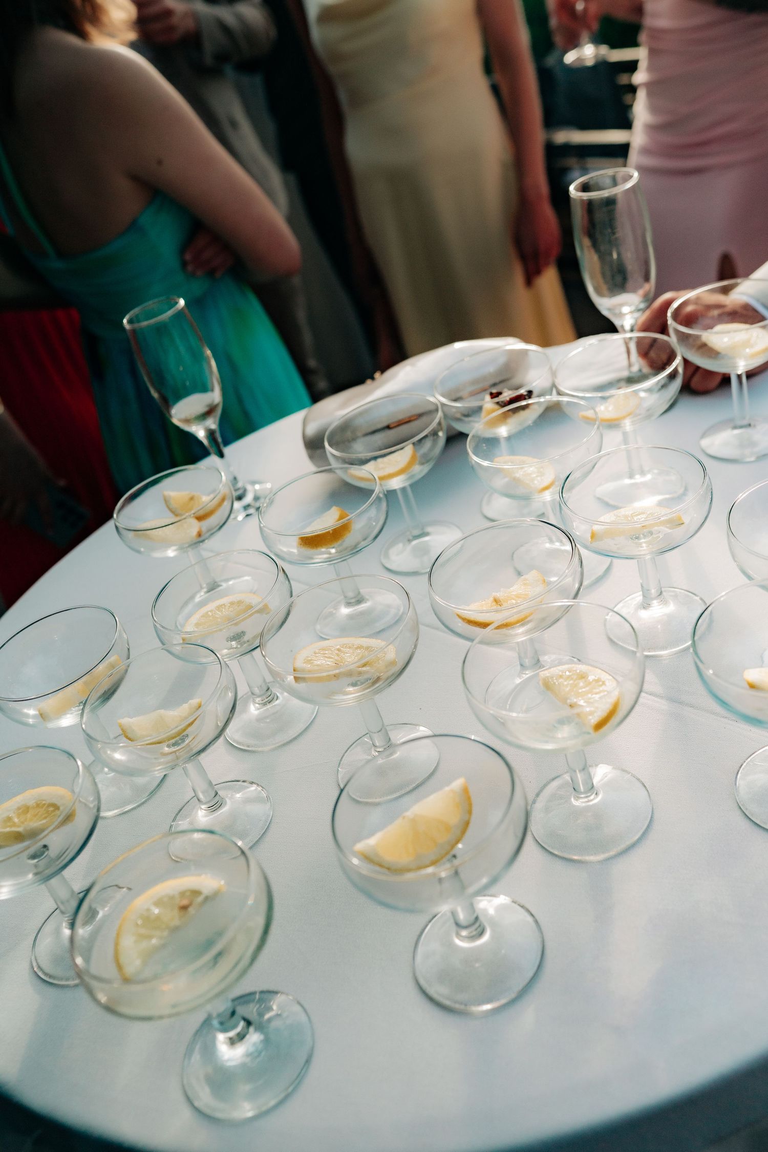 Wedding reception cocktail table with coupe glasses filled with white wine and lemon slices.