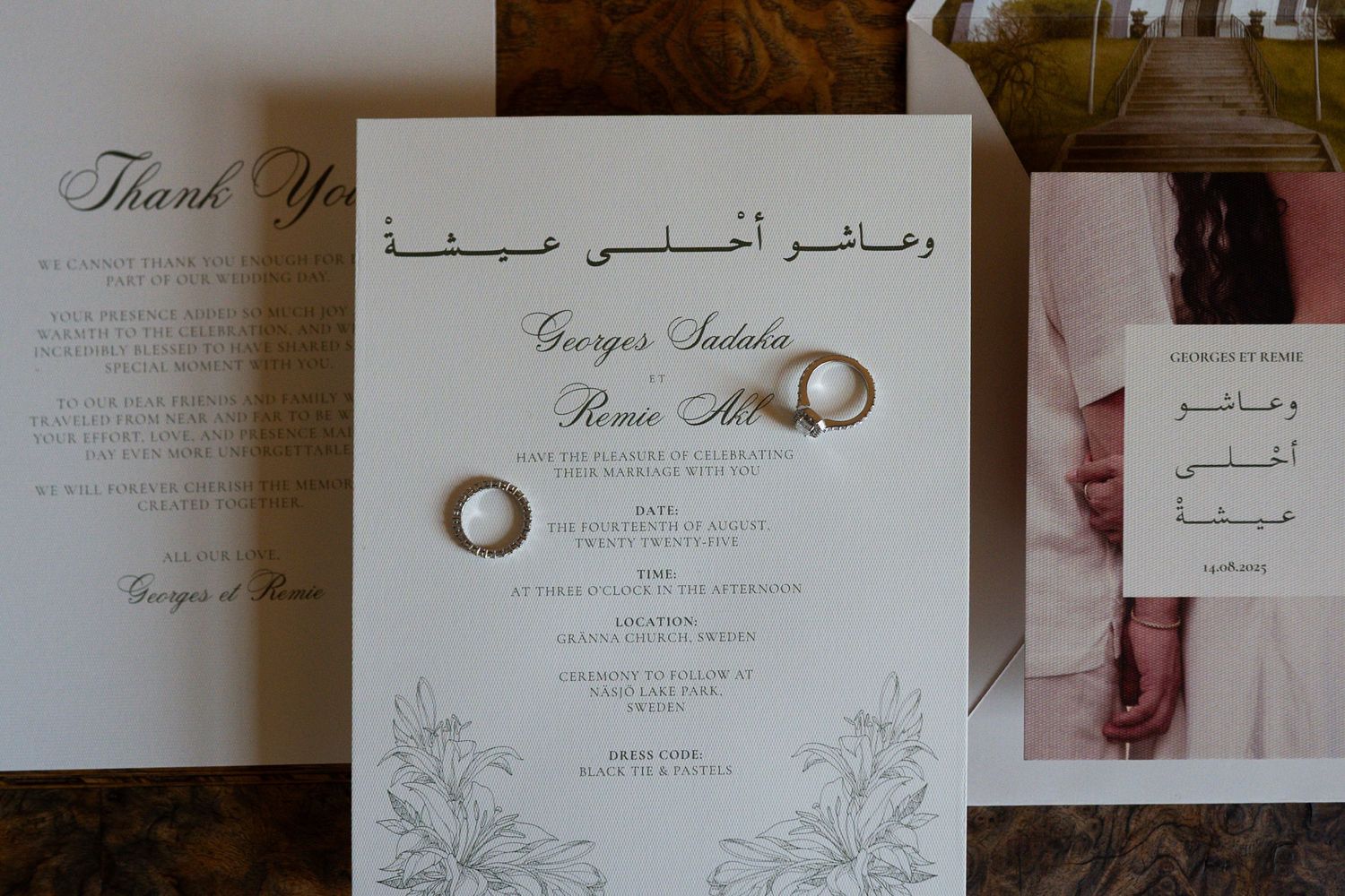 Bilingual Arabic and English wedding invitation suite with gold rings resting on white stationery.