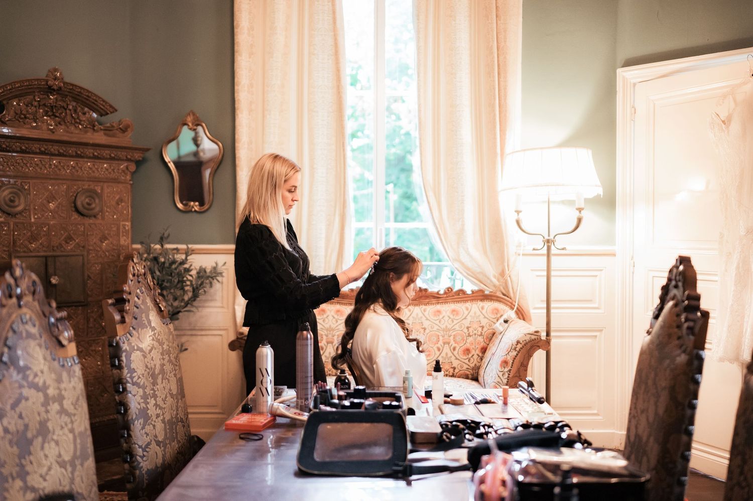 Bride getting her hair styled by a professional in an elegant chateau bridal suite.