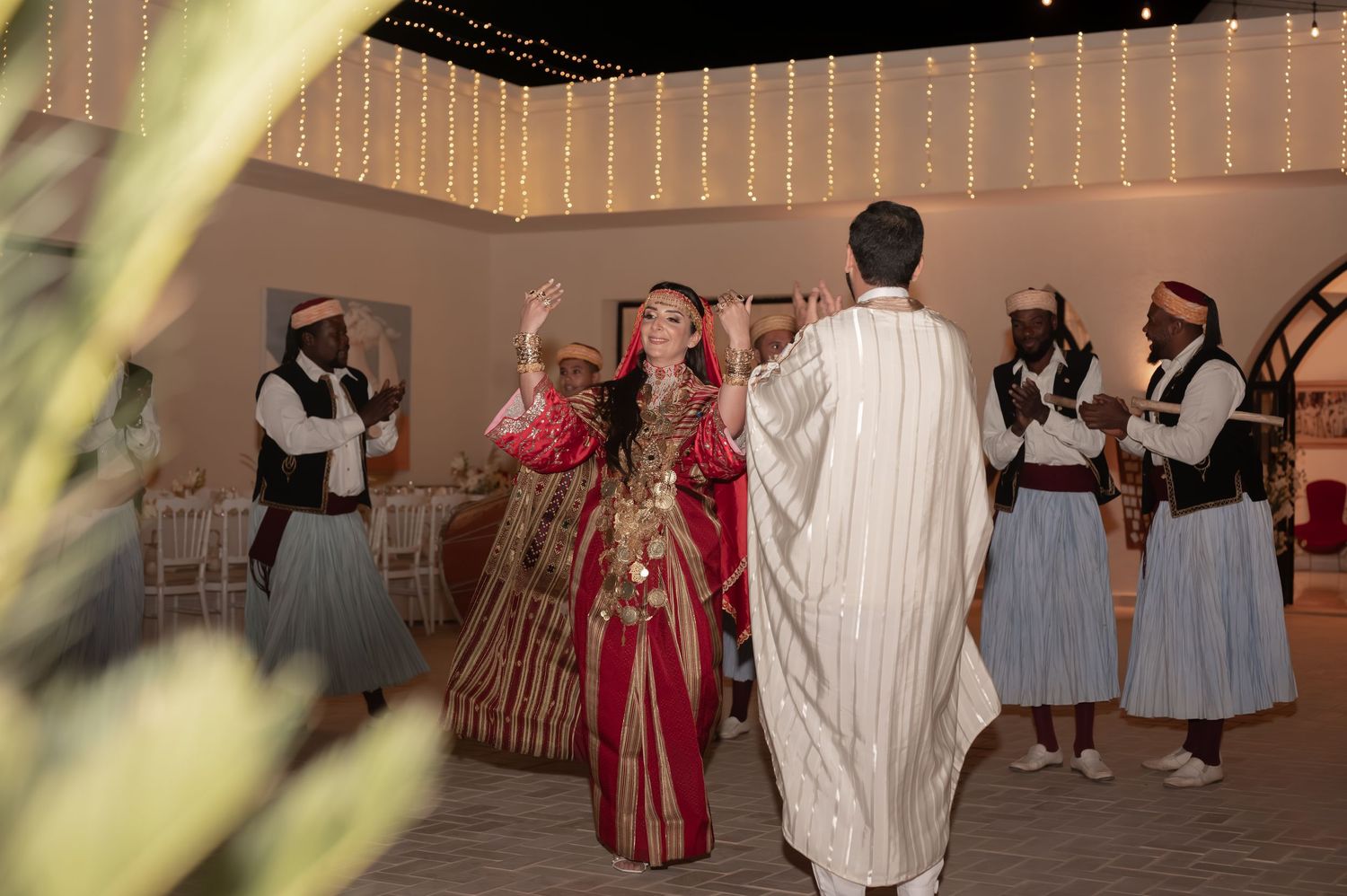 Bride and groom dancing together with traditional musicians at their wedding celebration.