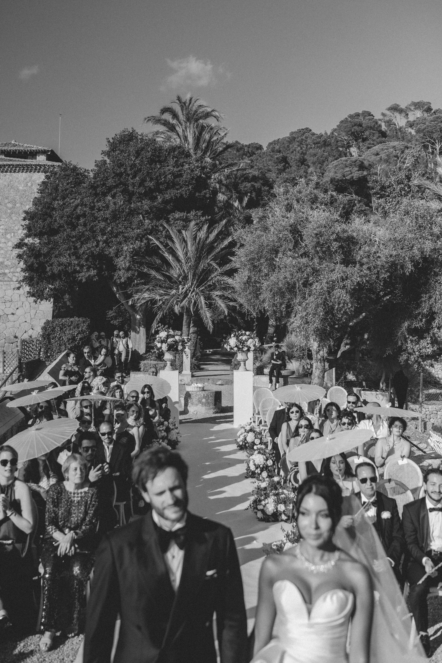 Black and white aerial view of bride and groom walking back down the aisle after their ceremony.
