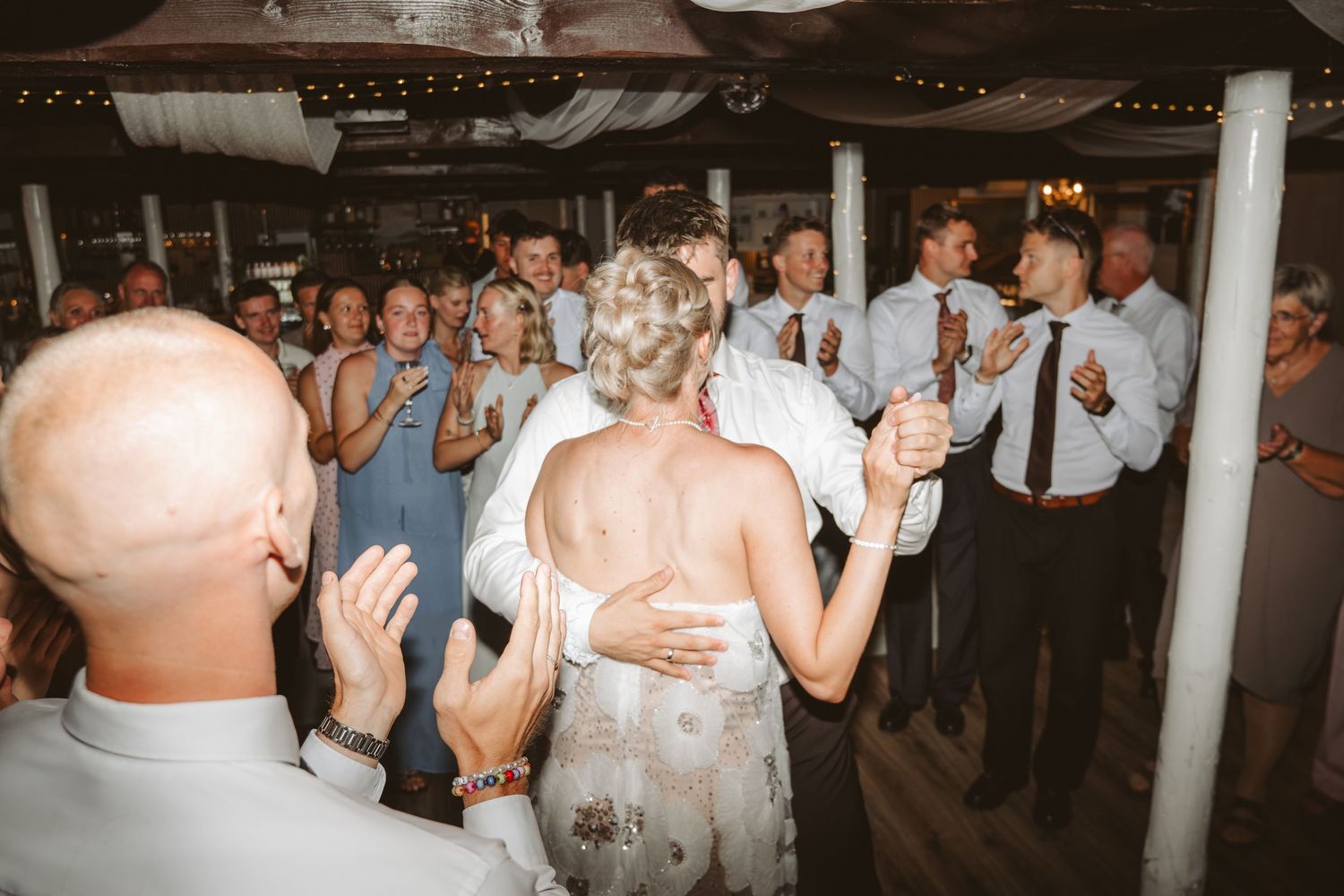 Brudepar danser omgivet af gæster på dansegulvet