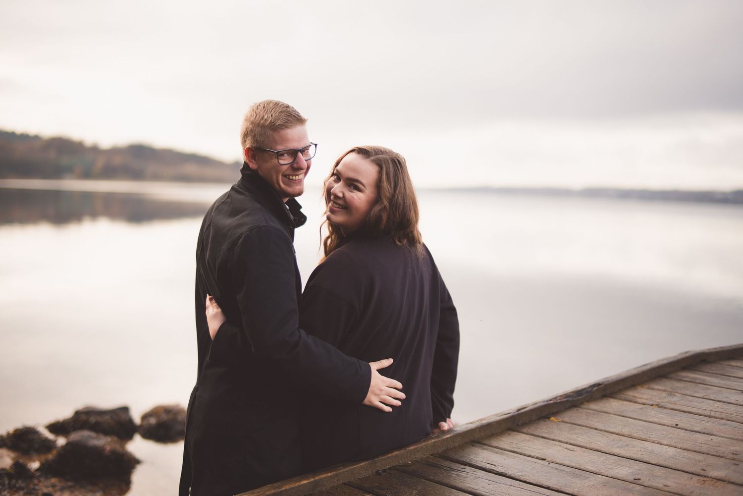 Smilende par står sammen ved vandet under deres prøvefotografering