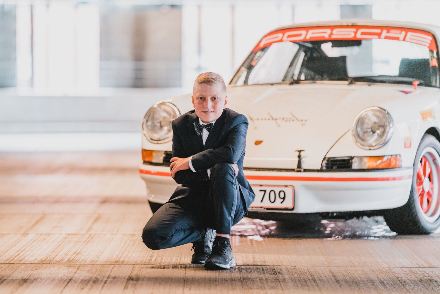 Konfirmand fotograferet foran en klassisk Porsche