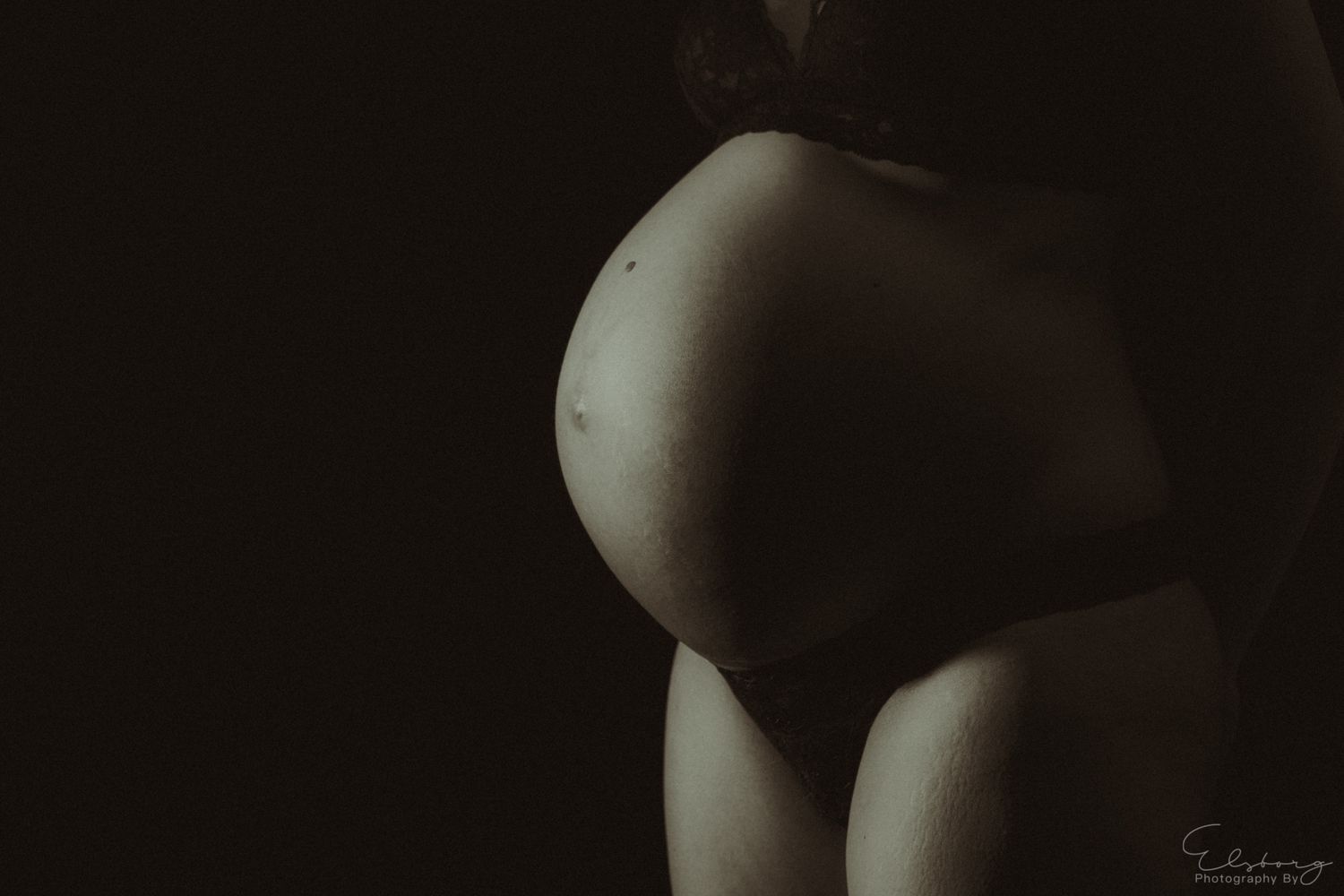 Stemningsfuldt portræt af gravid mave fotograferet i dæmpet lys