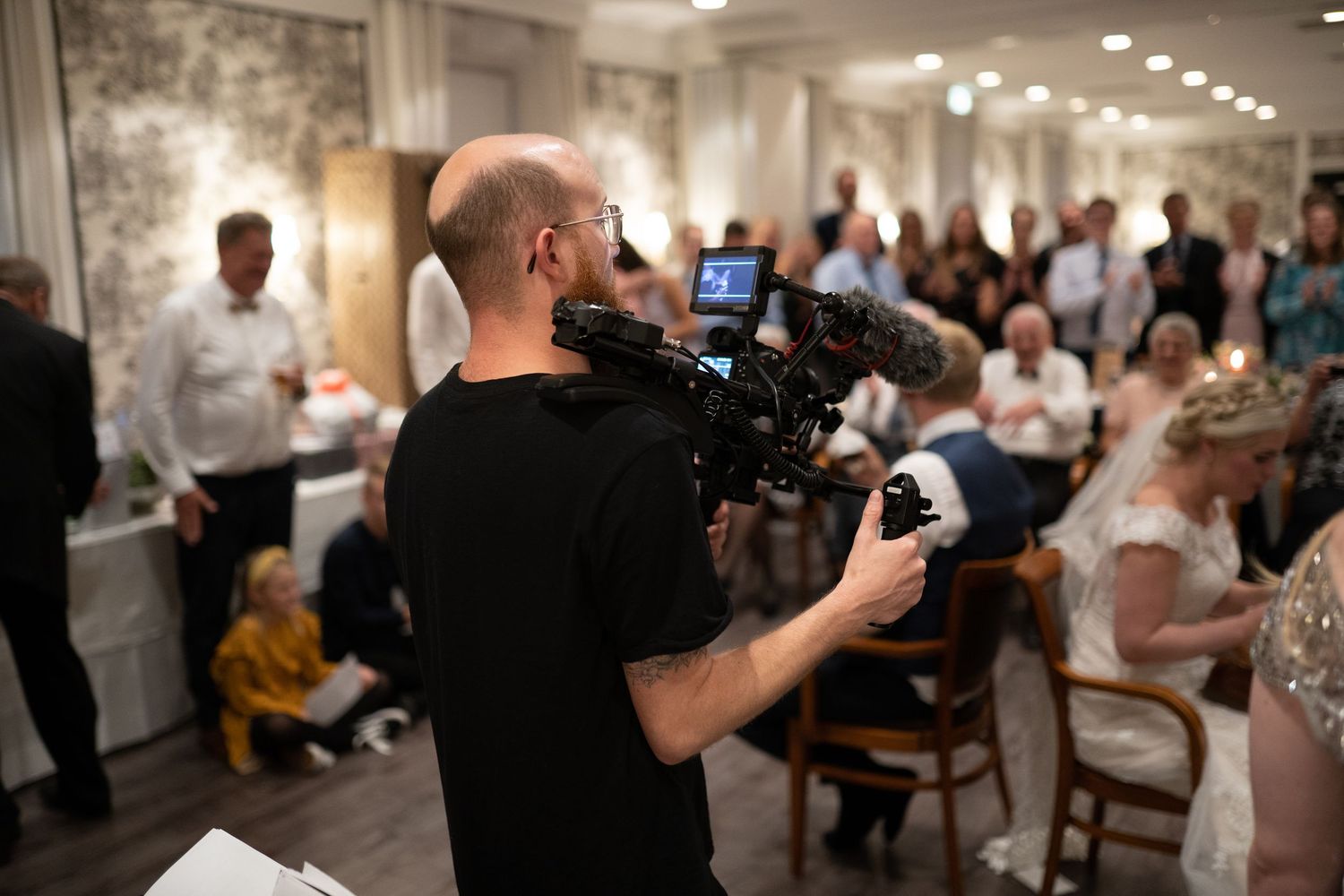 Bryllupsvideograf filmer under bryllupsfesten med professionelt videokamera
