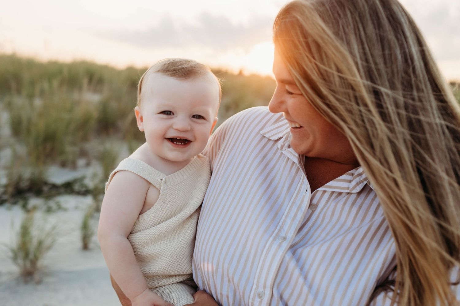 A tender moment captured on a sandy beach as two figures share laughter and joy in warm sunlight.