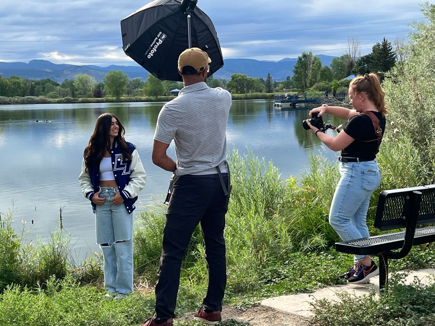 Behind the scenes showing dual-photographer team capturing a high school senior portrait near a lake in Northern Colorado