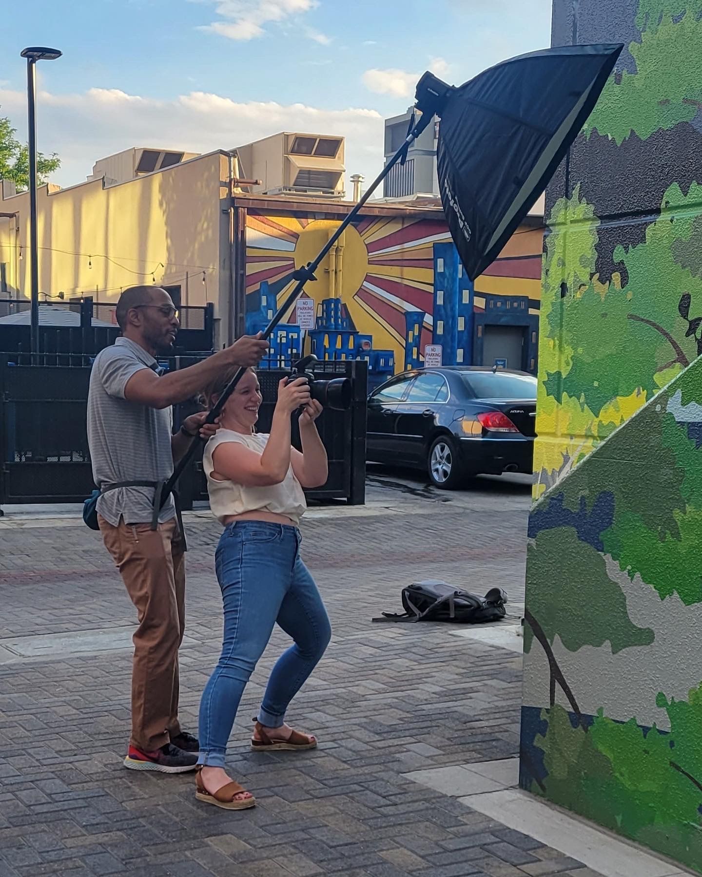 Behind the scenes of husband and wife dual-photographer team working together with lighting equipment on an urban shoot