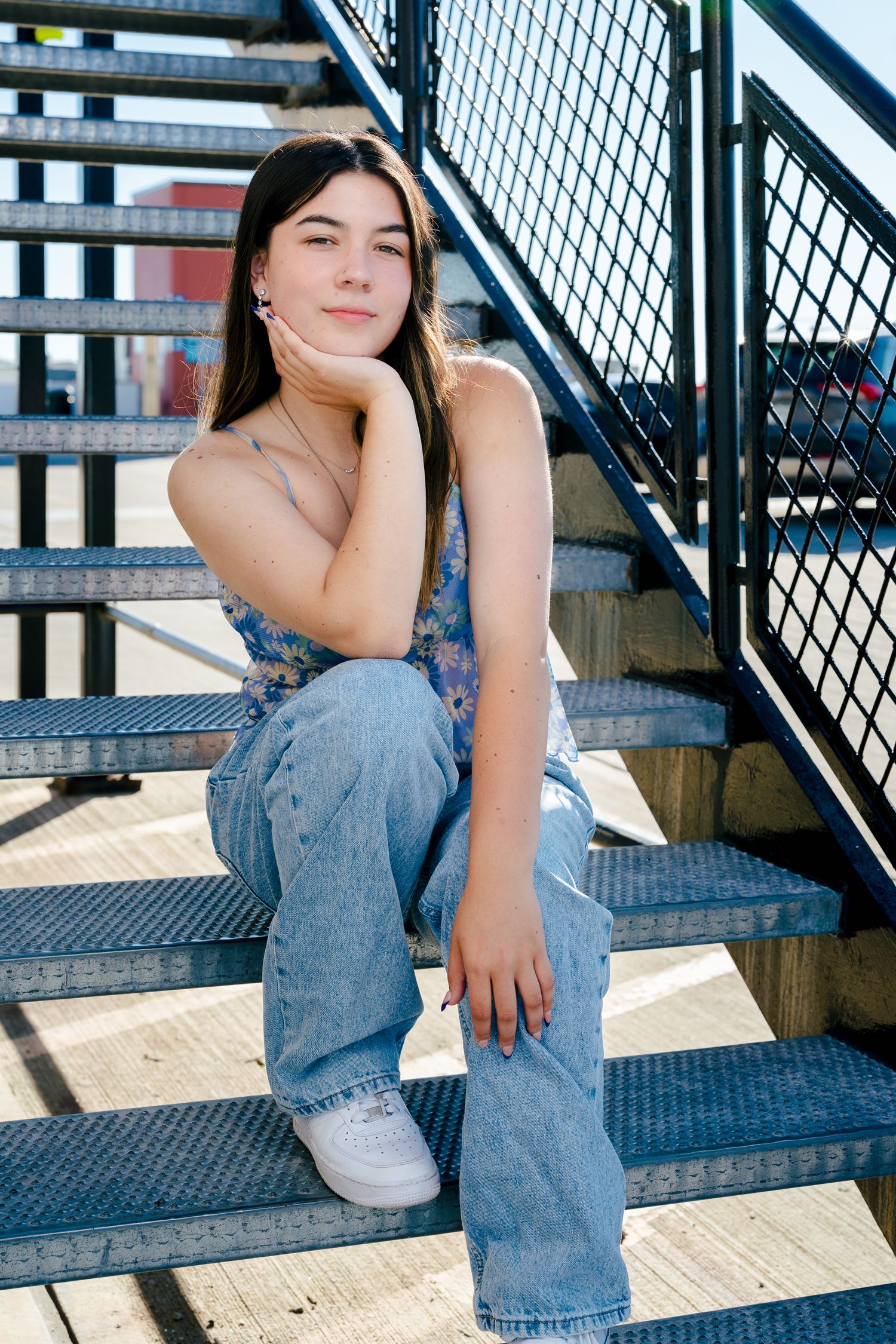 High school senior girl sitting casually on outdoor metal stairs for a portrait session in Northern Colorado