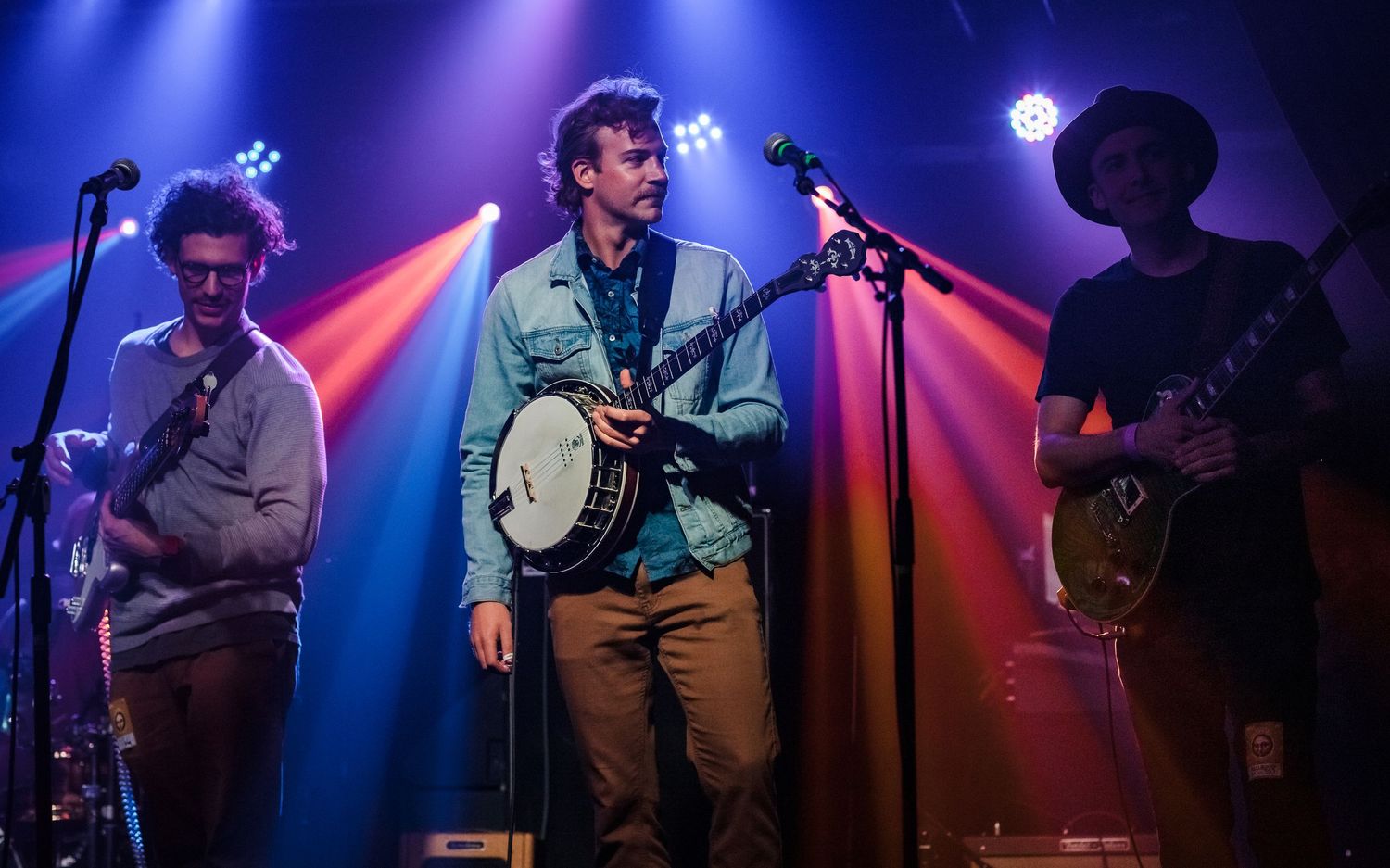 Live band performing on stage with banjo and guitars under dramatic blue and pink stage lights in Northern Colorado