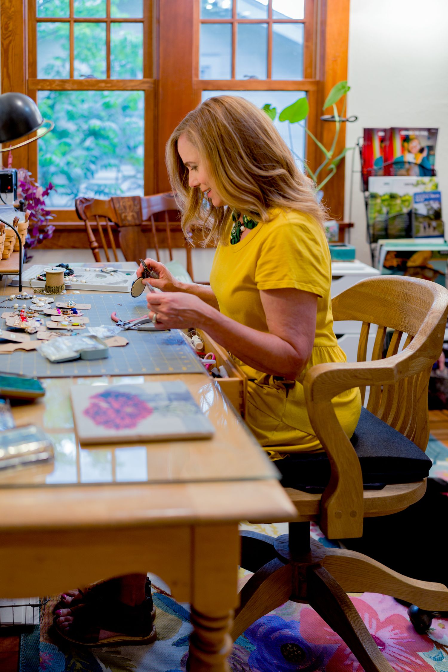 Small business owner painting and designing jewelry at her studio desk during a branding shoot in Northern Colorado