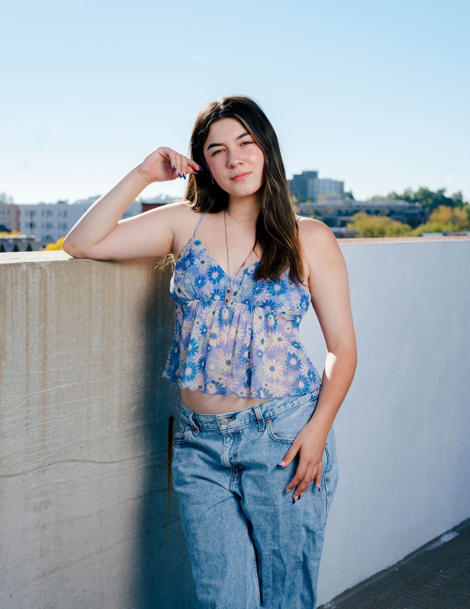 High school senior girl leaning against a concrete wall outdoors on a rooftop in Northern Colorado