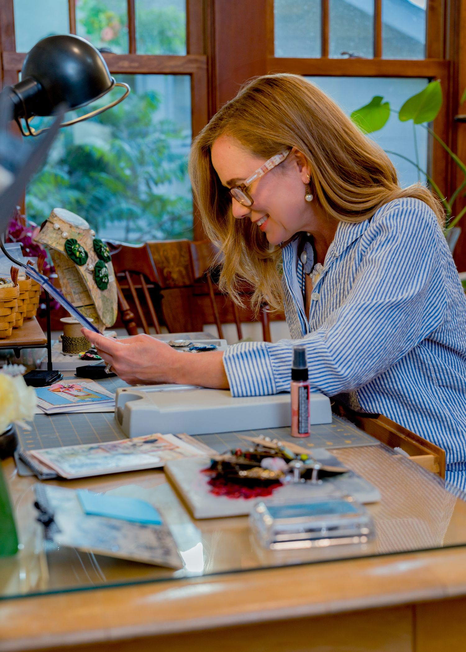 Small business owner crafting handmade jewelry at her desk during a commercial branding shoot in Northern Colorado
