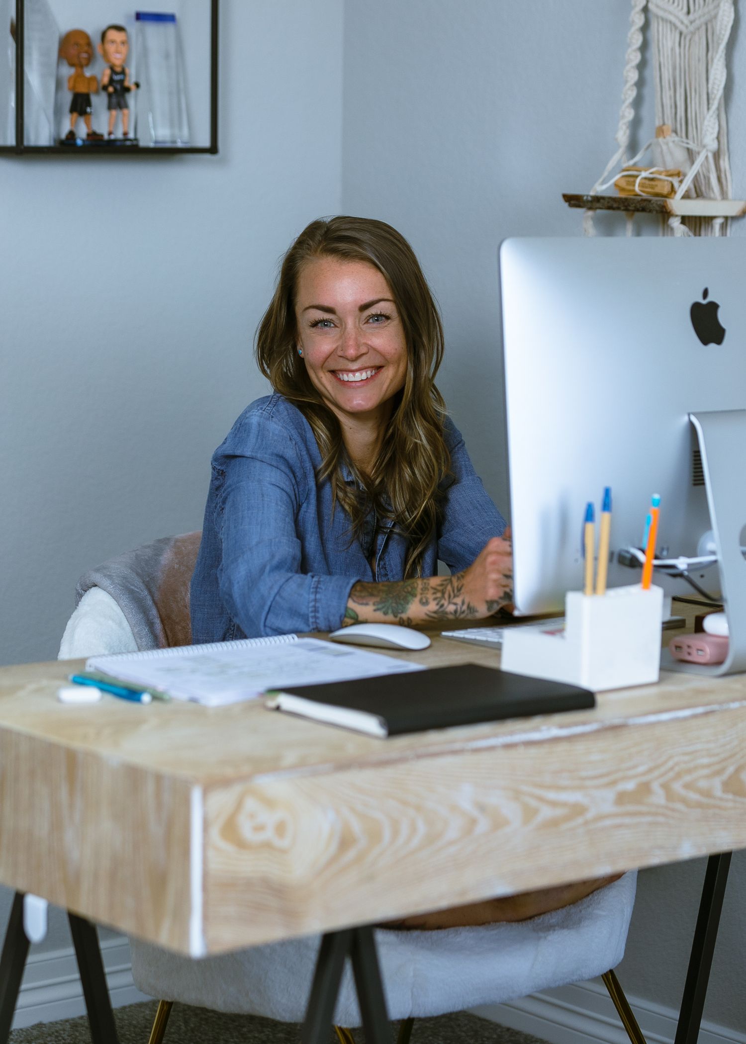 Creative entrepreneur smiling at her desk in a bright home office during a commercial photo session in Northern Colorado