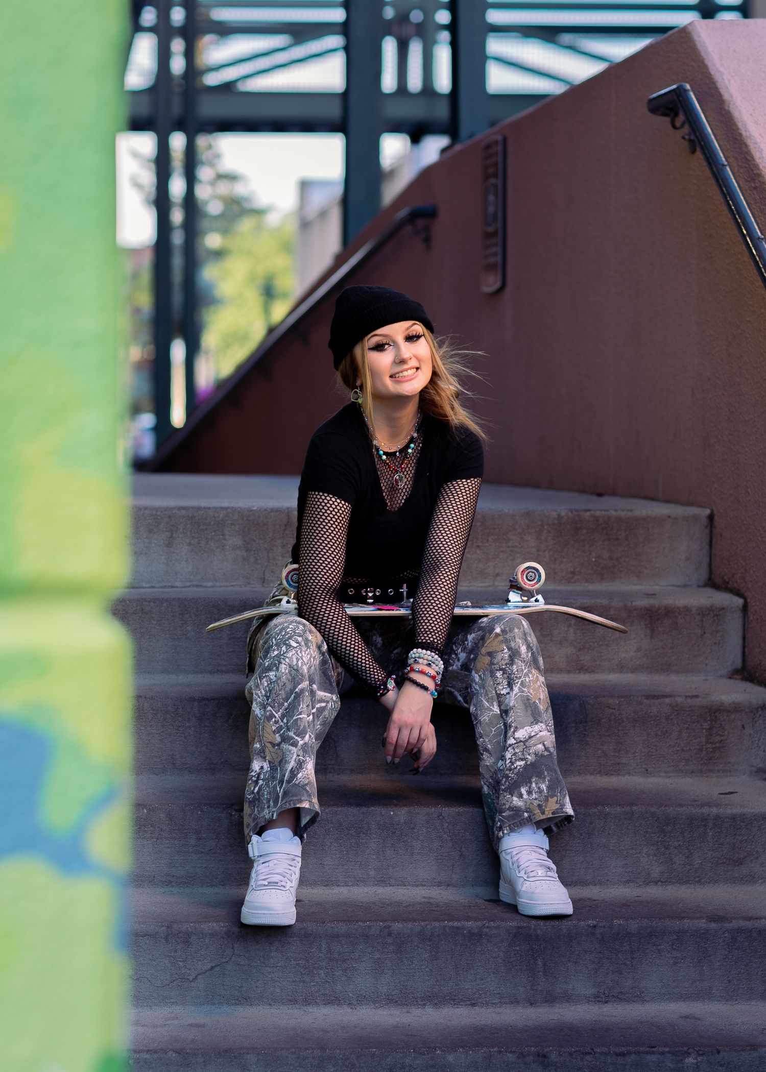 Edgy senior portrait of a girl with a skateboard sitting on outdoor urban stairs in Northern Colorado