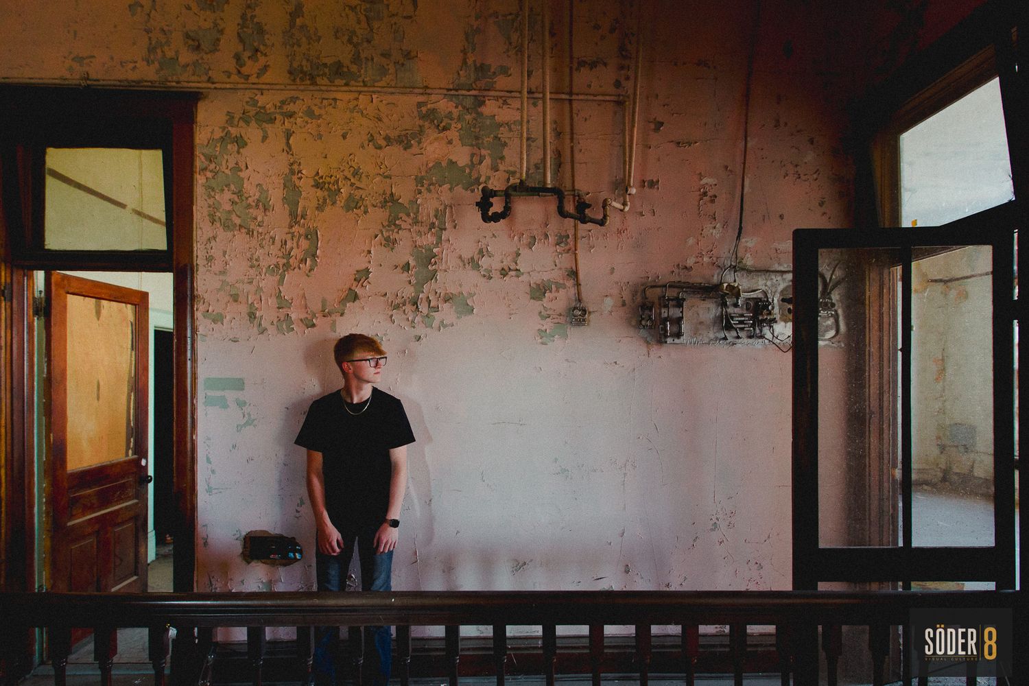 high school senior boy posed against wall with light and shadow
