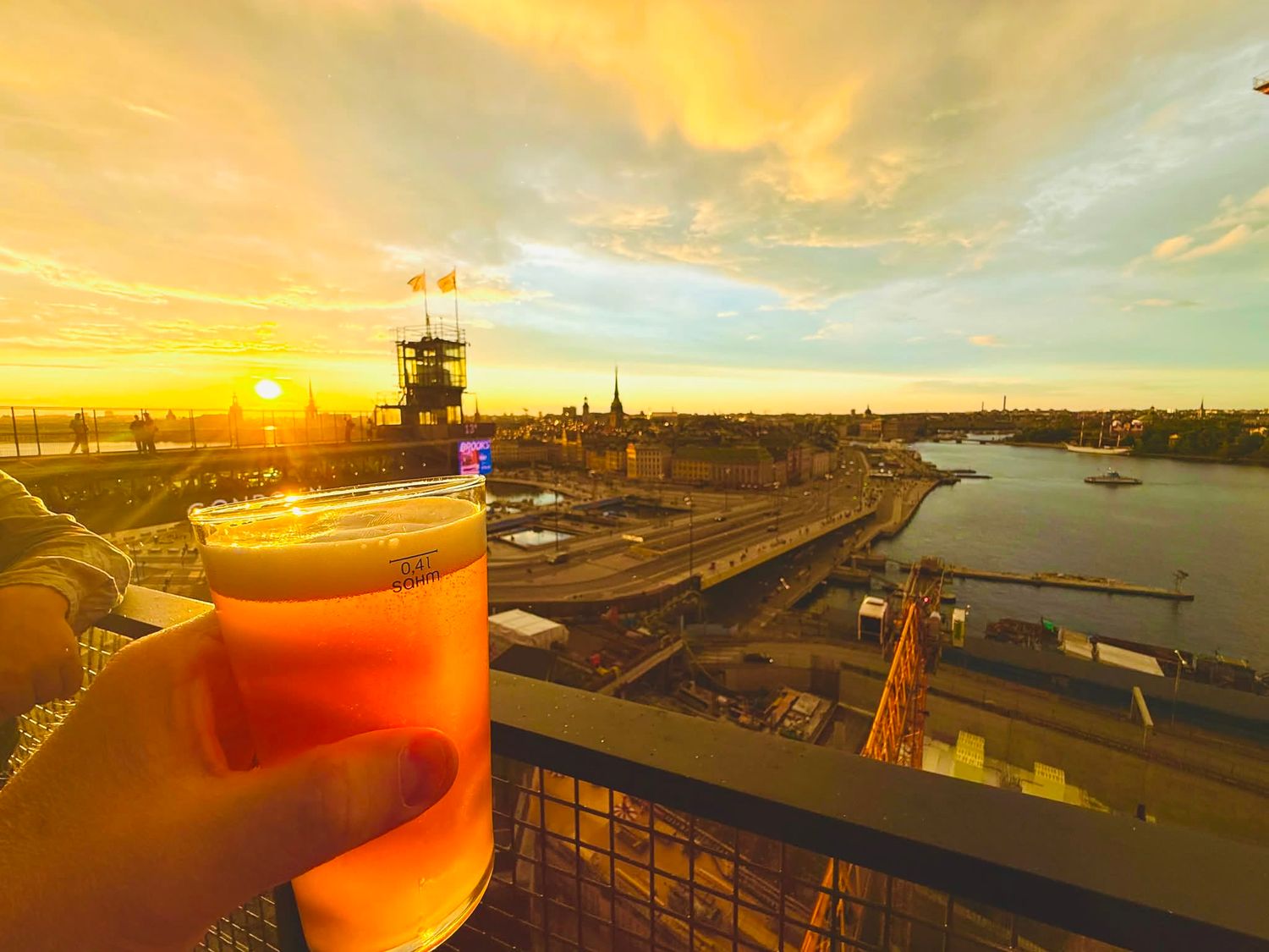 glass of beer overlooking stockholm at sunset